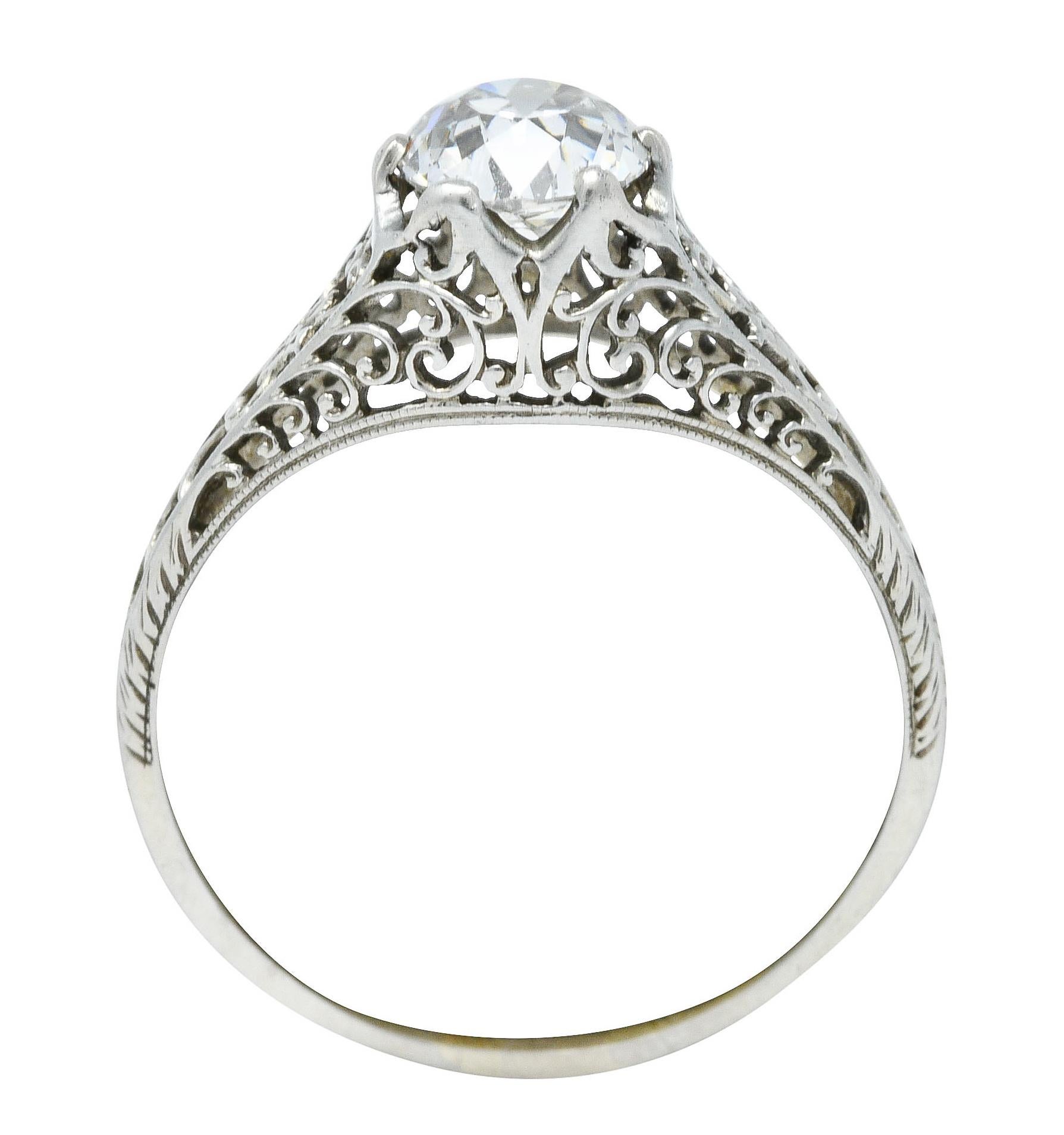 Centering an old mine cut diamond weighing 1.10 carats - J color with VS1 clarity

Set in a pierced filigree mounting with a scrolling design throughout

Completed by foliate accents at shoulders and shank

Stamped 18K-W for 18 karat white