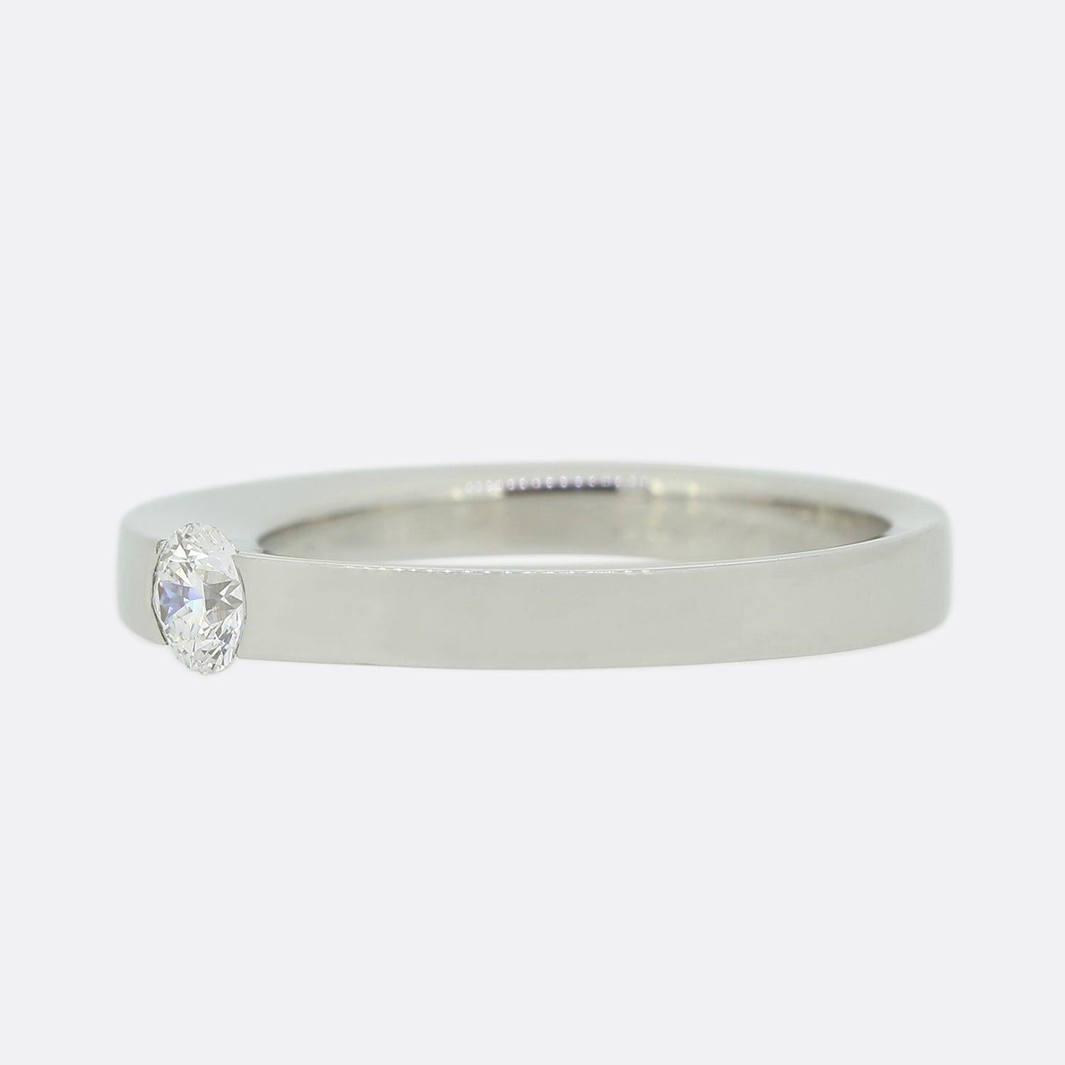 Si tratta di un bellissimo anello con solitario di diamanti del designer di gioielli di lusso Cartier. L'anello ospita un singolo diamante rotondo taglio brillante che si trova in una montatura a metà castone. Il design è riconoscibile come quello