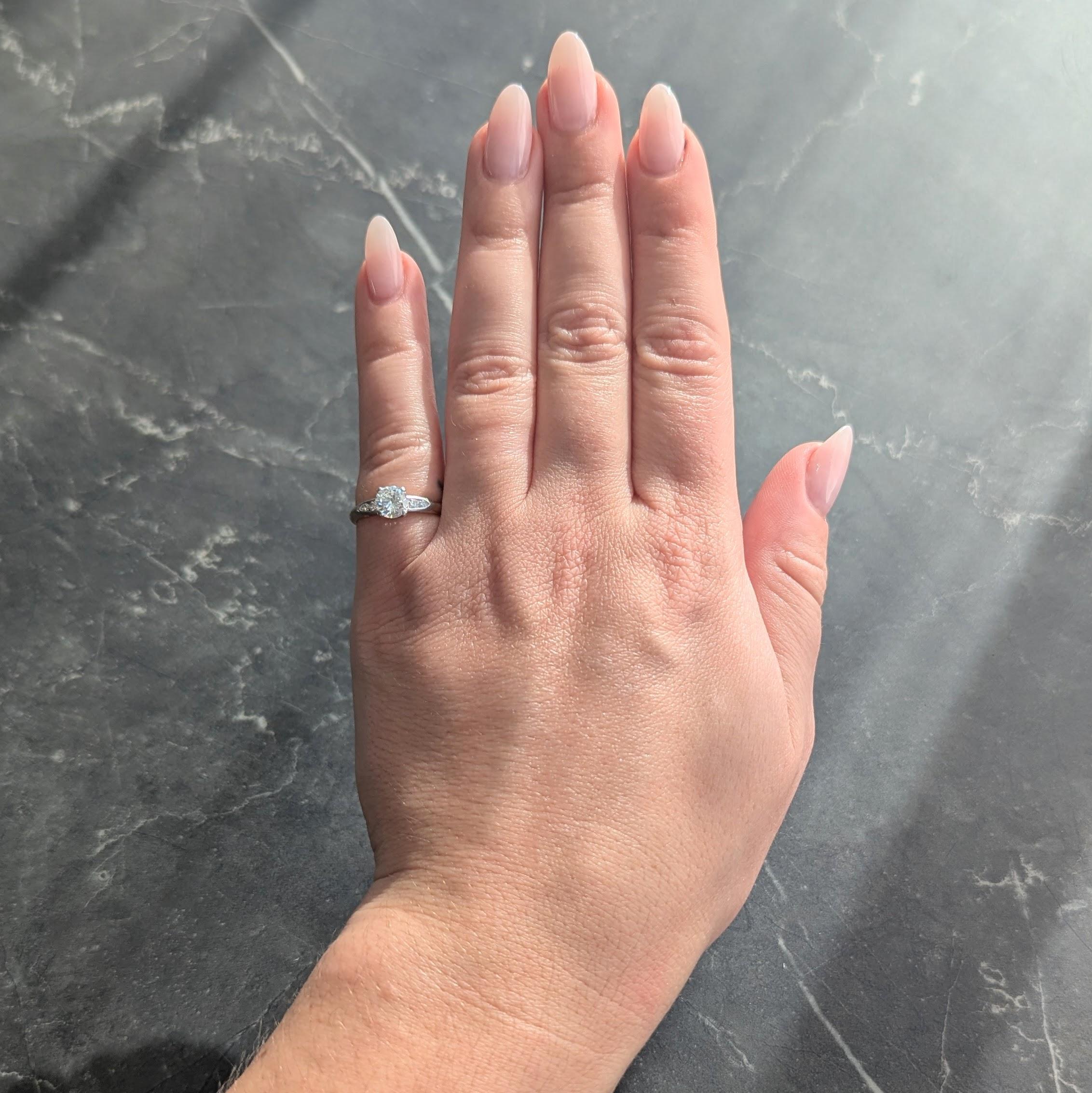 Centrado en un diamante de talla de transición con un peso aproximado de 0,61 quilates - color H con claridad SI1
Engastada en una cabeza de forma cuadrada y flanqueada por hombros catedral en platino
Cuenta engastada con diamantes talla única con