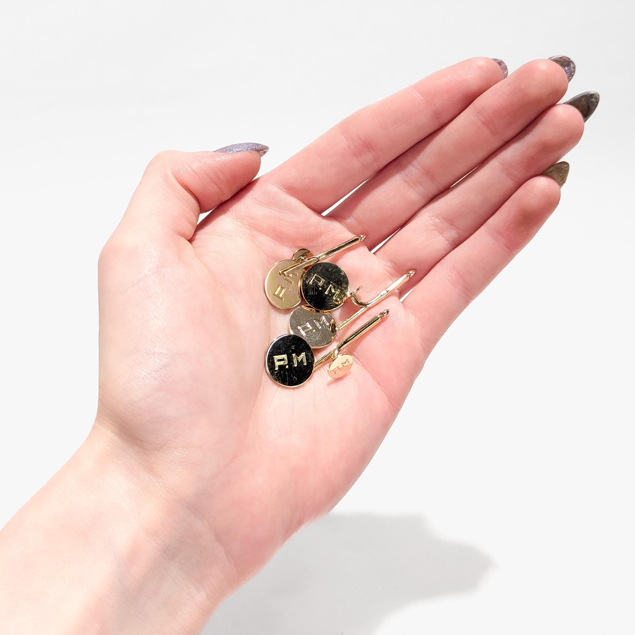 A fine pair of gold cufflinks and matching shirt stud dress set.

By Cartier.

In 14 karat yellow gold. 

Each monogrammed to the face for 'P.M'.

Marked Cartier / 14K to the reverse of both studs & cufflinks.

Simply a wonderful set of gold formal