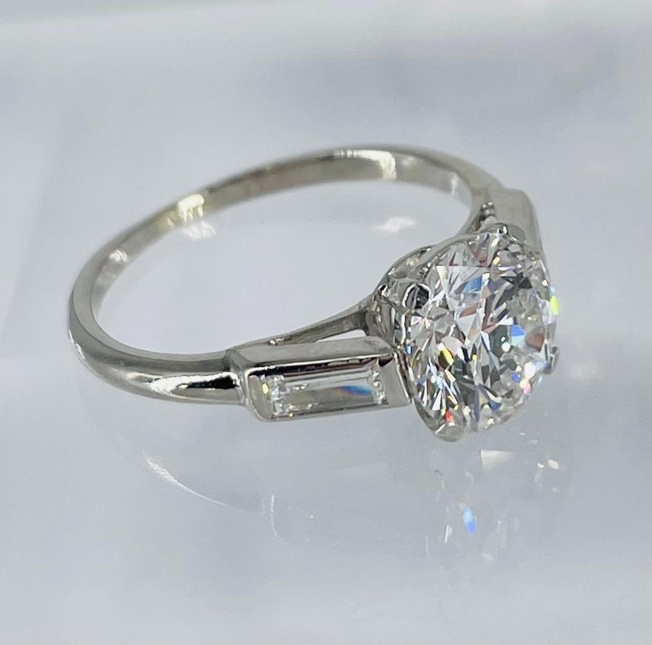 An exquisite piece by Cartier, this engagement ring features a 1.57 carat round diamond certified by GIA as F color and VS1 clarity. The setting is crafted in platinum with Cartier's signature details: charming tab prongs, bezel set side stones, and
