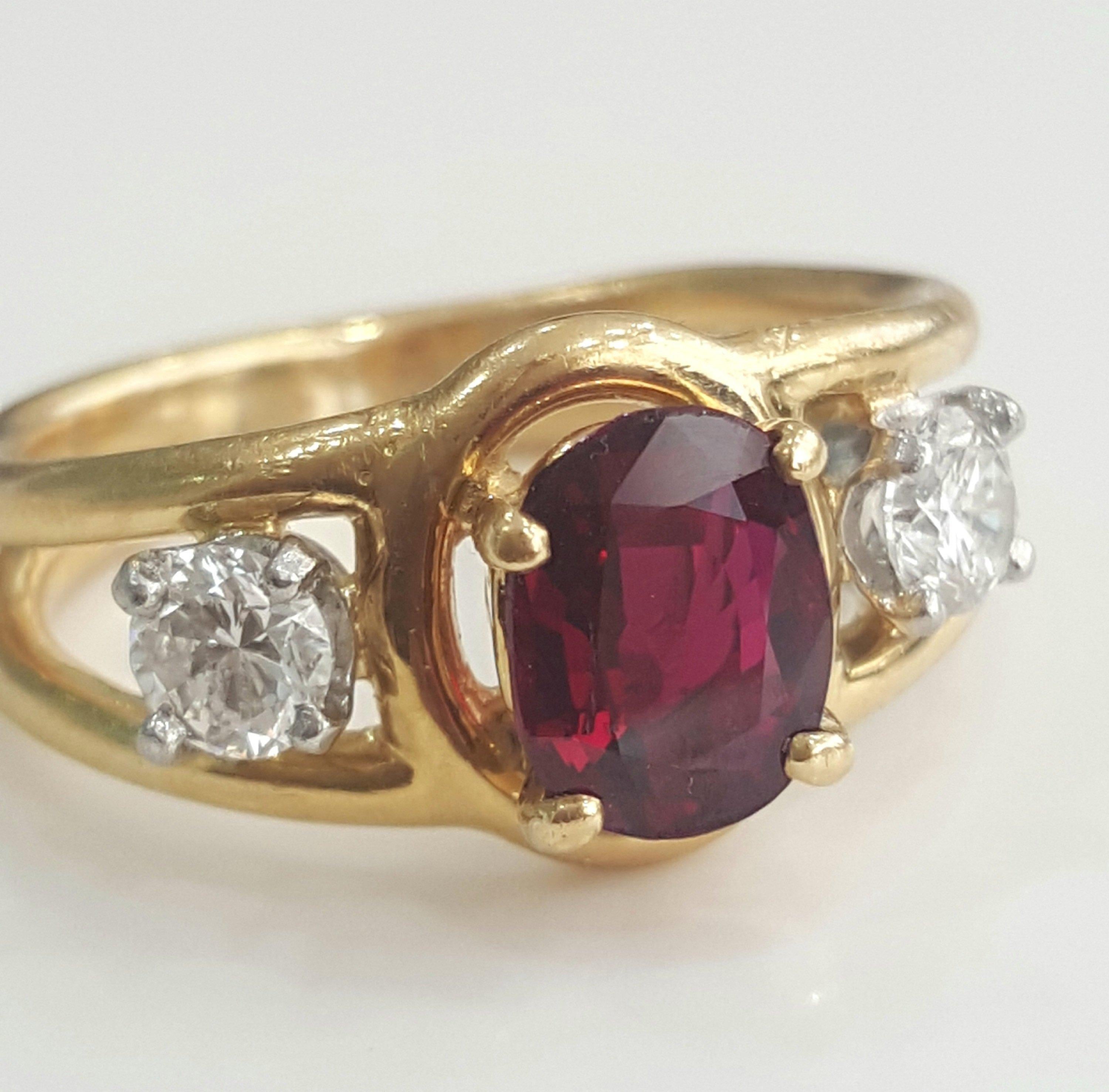 This beautiful ring centers an oval ruby heat weighing 1.30 carat and is flanked by two white round brilliant diamonds weighing a total of 0.40 carat with G/H color and VS clarity. There is a Cartier stamp on the shank. The gold weight is 5.06