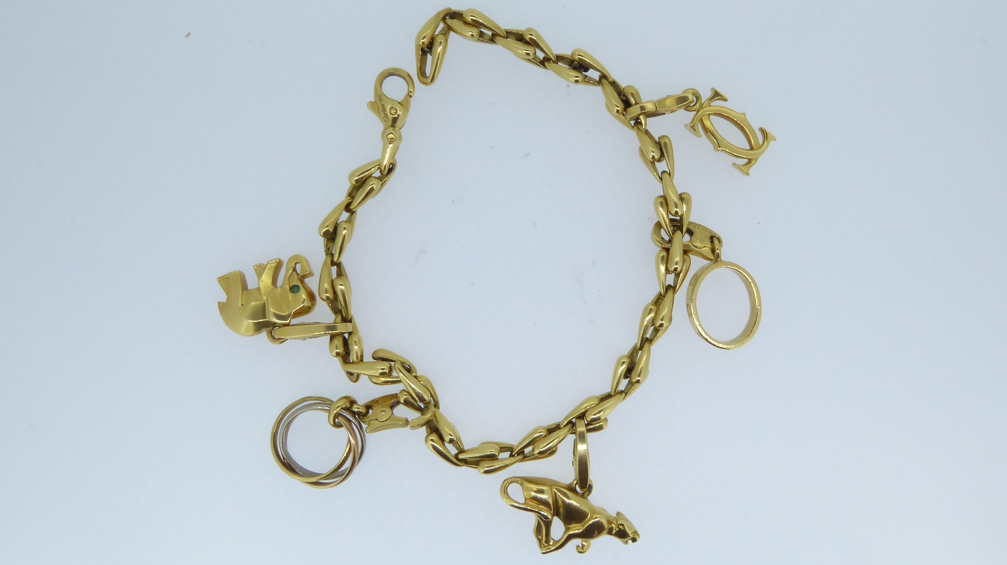Cartier 18 Carat Yellow Gold 5 Charm Bracelet. Adorned with 5 various charms including an elephant, panther, trinity charm, love charm and the double-C. Each charm signed 