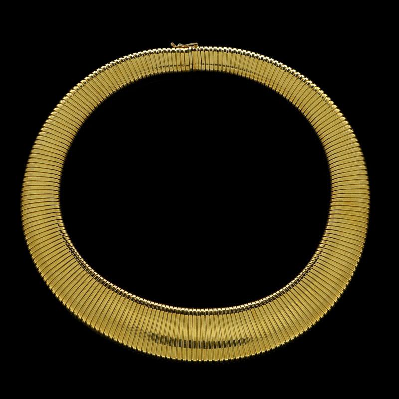 18 Carat yellow gold signed Cartier, stamped K18 and numbered 548 to the tongue
16” long, centre front 0.9” wide, centre back 0.5”
89 grams

A wide flattened gas-pipe link necklace by Cartier c.1950s, the highly flexible necklace of gently tapering