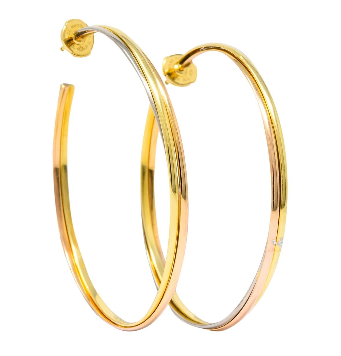 Large hoop style earrings comprised of three segments of intertwined yellow, white, and rose gold

With a high polish finish

Completed by posts and la pousette backs

From Cartier's Trinity collection

Fully signed Cartier with 750 stamp for 18