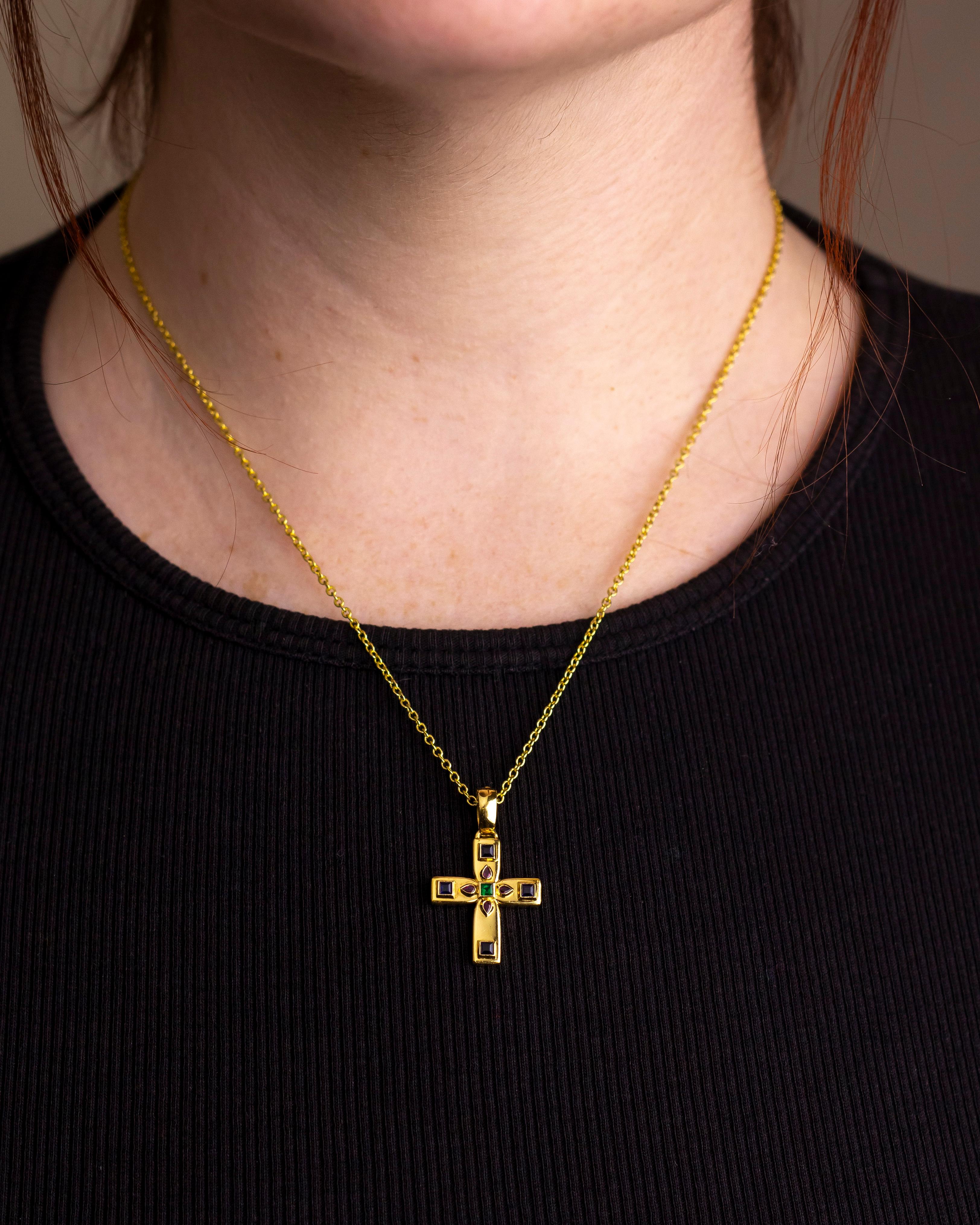 This charming gold cross was made by Cartier in the 1990s. Crafted from 18 karat yellow gold the cross is set with four square cut blue sapphires, four pear shape rubies and a central square cut green emerald. The cross is finished with a plain gold