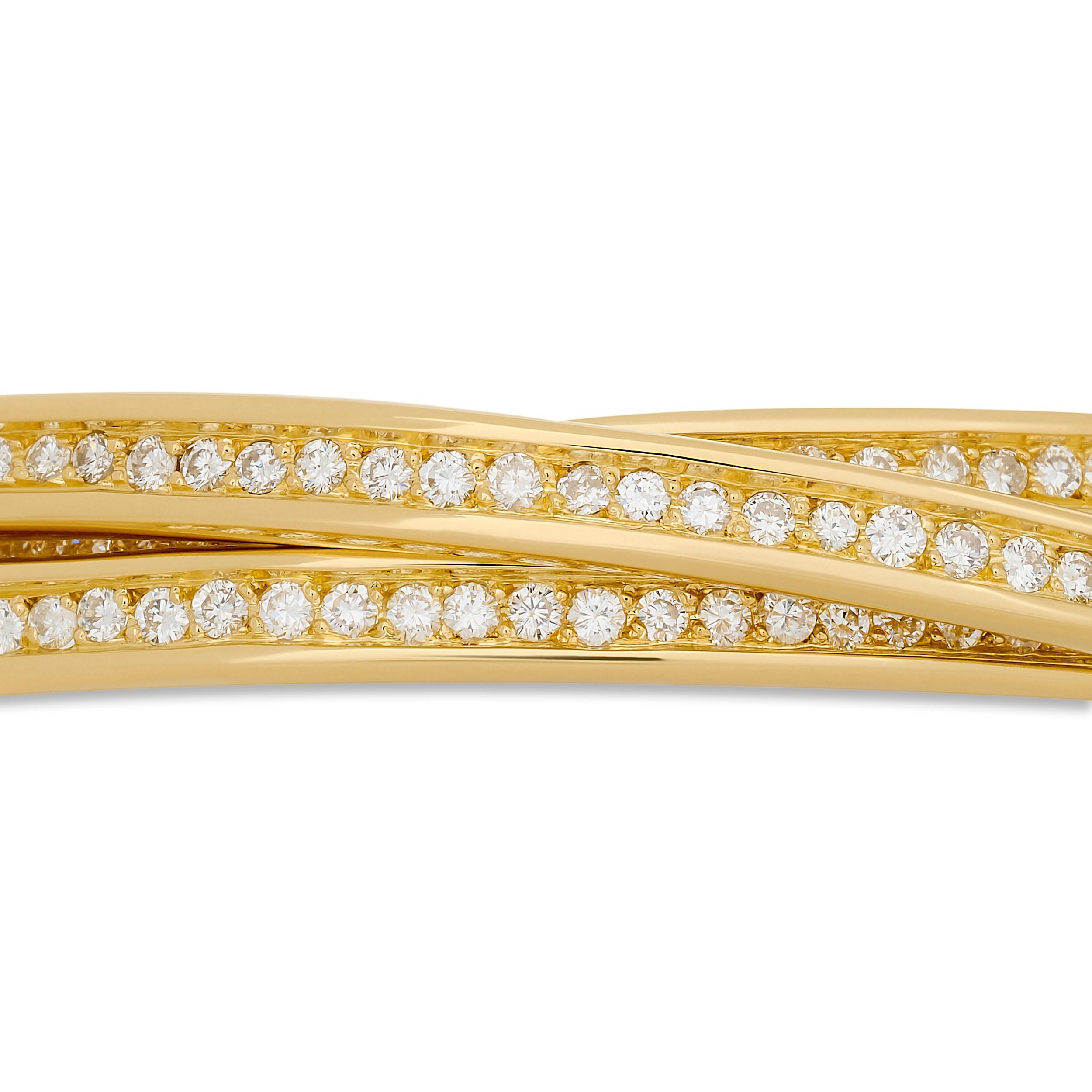 This Cartier Trinity Rolling bangle bracelet features three intertwined bands of 18 karat yellow gold, each delicately set with sparkling diamonds, creating a harmonious and elegant piece that embodies the iconic Trinity design.

Round diamonds