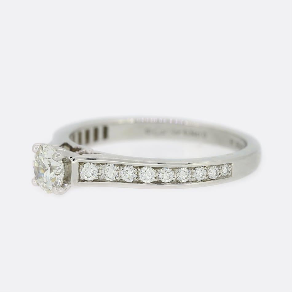This is a platinum diamond solitaire ring from the world renowned jewellery designer Cartier. The ring forms part of the iconic '1895' collection and features a stunning 0.34 carat round brilliant cut diamond. Each shoulder also plays host to a