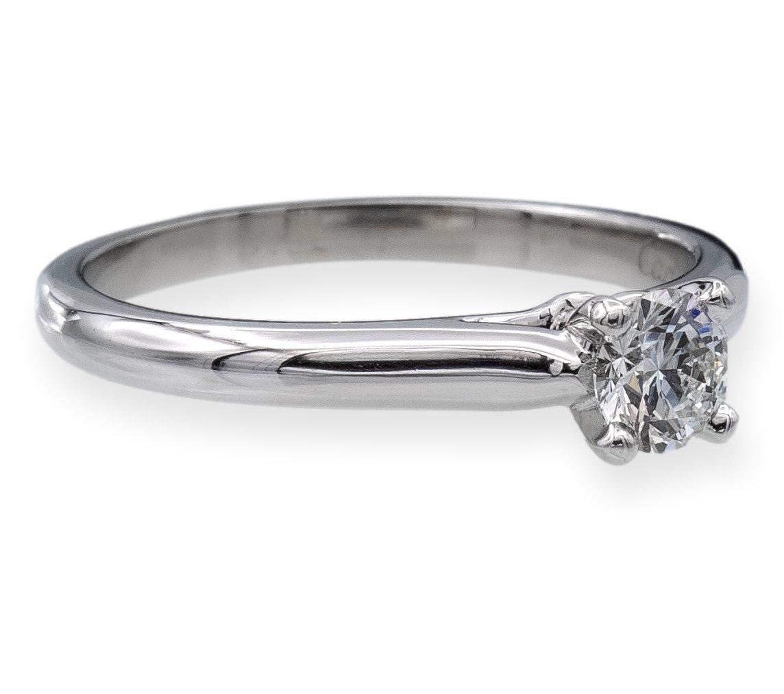 This Cartier engagement ring from the 1895 collection is a masterpiece of fine craftsmanship, made from premium platinum with a stunning 0.25 carat round brilliant cut diamond at its center. The diamond is graded as F color and VS1 clarity by the