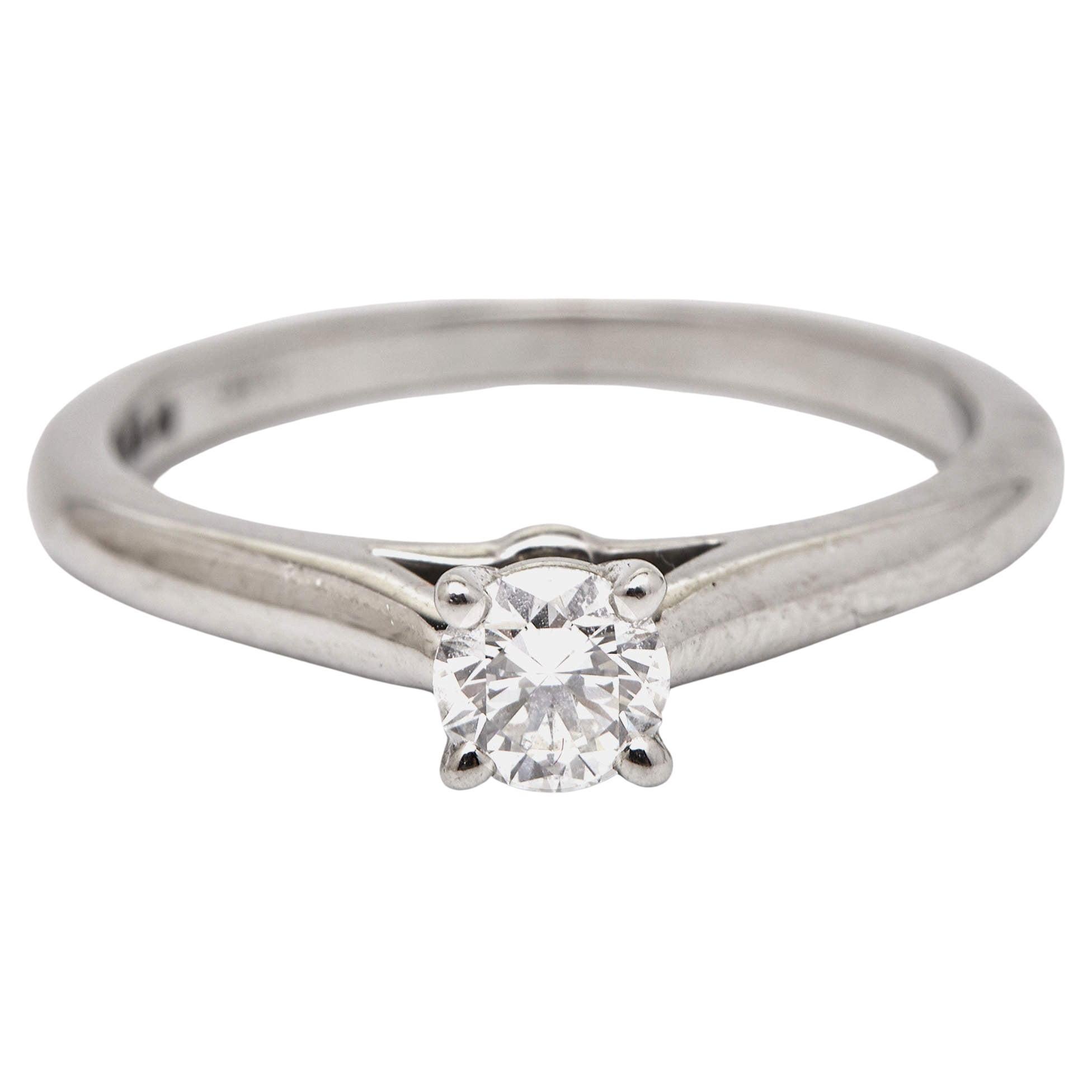 Cartier's 1895 solitaire ring is a carefully sculpted silhouette set to become your favorite everyday jewelry. This Cartier solitaire ring for women is made of platinum, and it has a 0.24 ct center diamond hoisted on a four-prong setting, catching