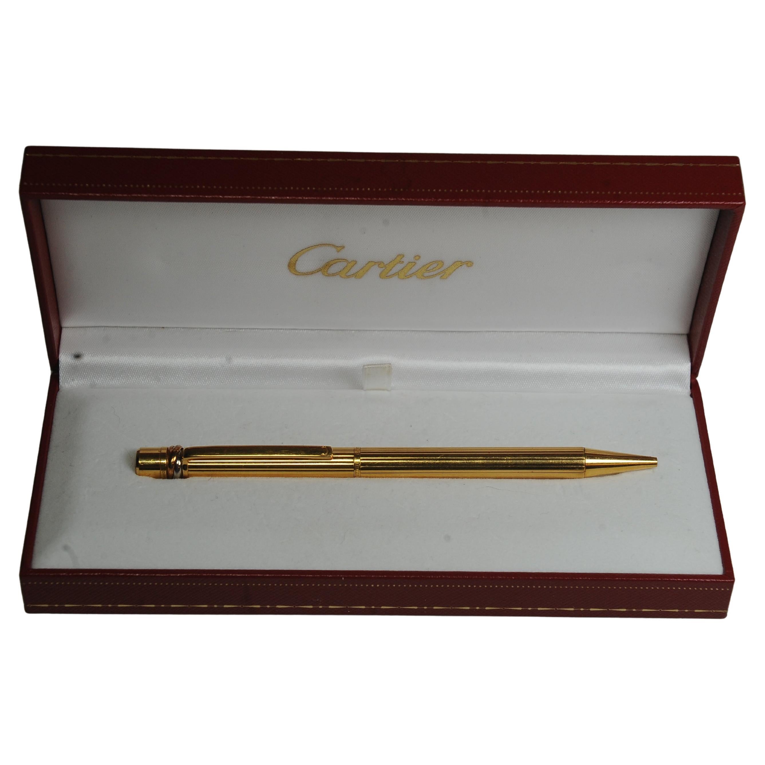 Penna a sfera Trinity a coste placcata oro 18ct Cartier in scatola originale Cartier, Made In Paris, fornita con scatola di presentazione rossa Cartier

Le penne Cartier sono disegnate da Cartier e prodotte da Montblanc. Questa collaborazione
