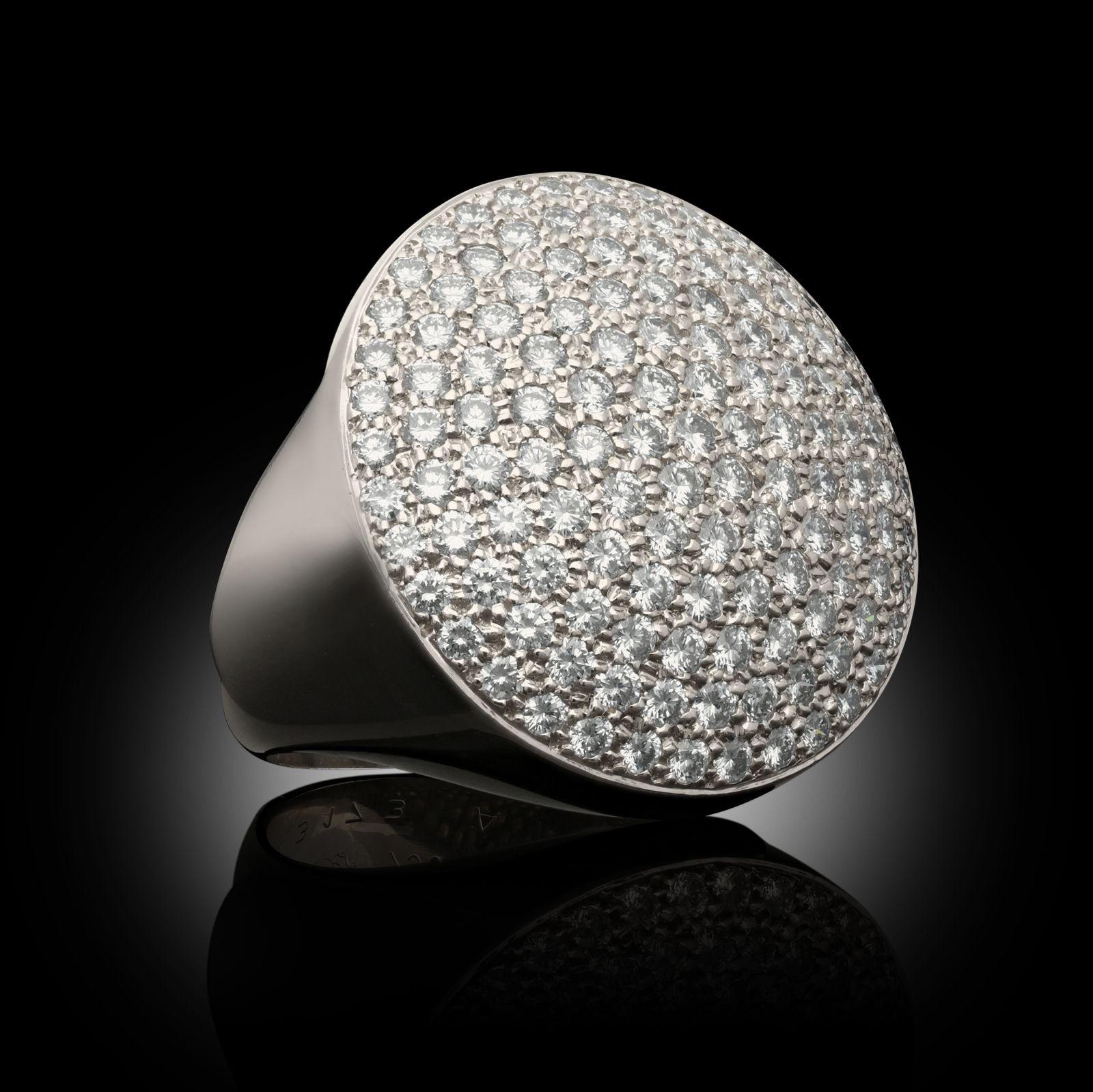 A striking and bold 18ct white gold and diamond cocktail ring by Cartier c.2000s, of large circular form, the gently domed head fully pavé set with round brilliant cut diamonds in 18ct white gold to tapering shoulders and a plain band. This would