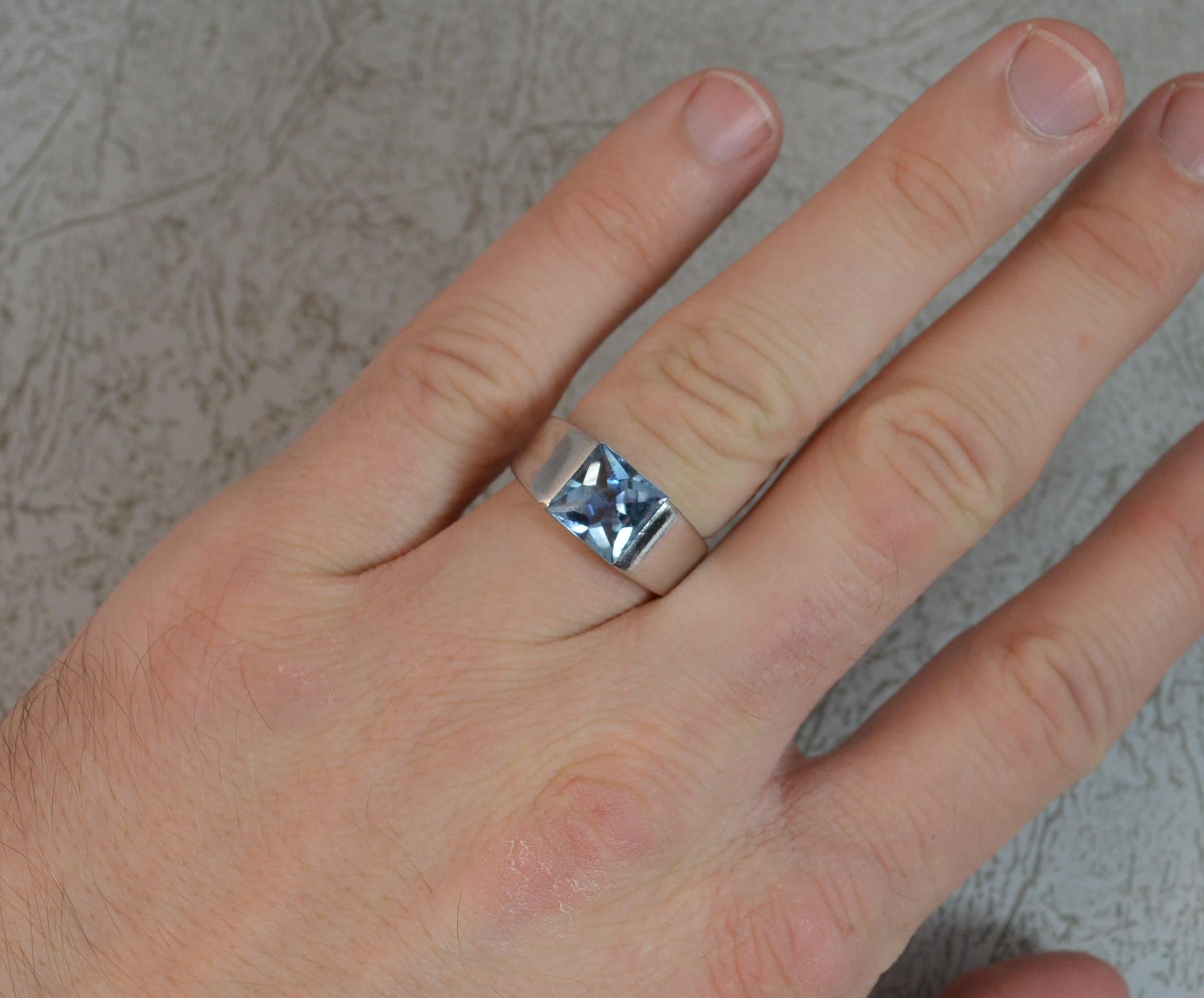 A Cartier designer Tank ring.
18 carat white gold example.
8mm square cabochon blue topaz to centre.

CONDITION ; Very good. Crisp design. Clear hallmarks. Light wear only. Please view photographs.

WEIGHT ; 12.6 grams
SIZE ; L 1/2 UK, 6 US
DATE ;