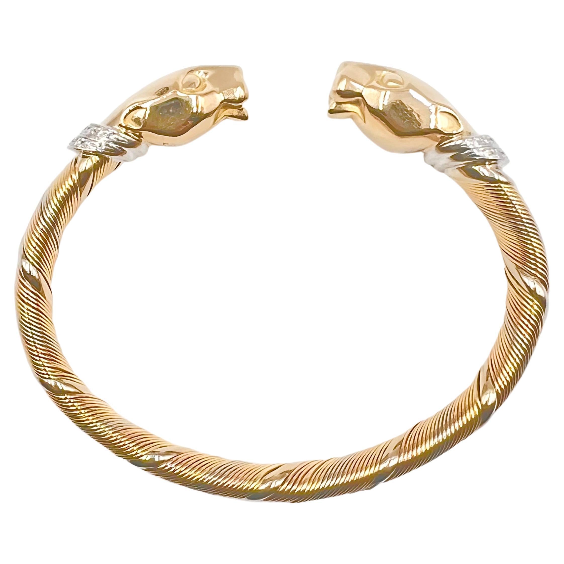 Cartier flexible cuff bracelet with polished, double panther heads in 18k yellow gold with 18k white gold collars accented by thirty-six round brilliant-cut diamonds weighing approximately 0.50 total carats. The main section of the bracelet is