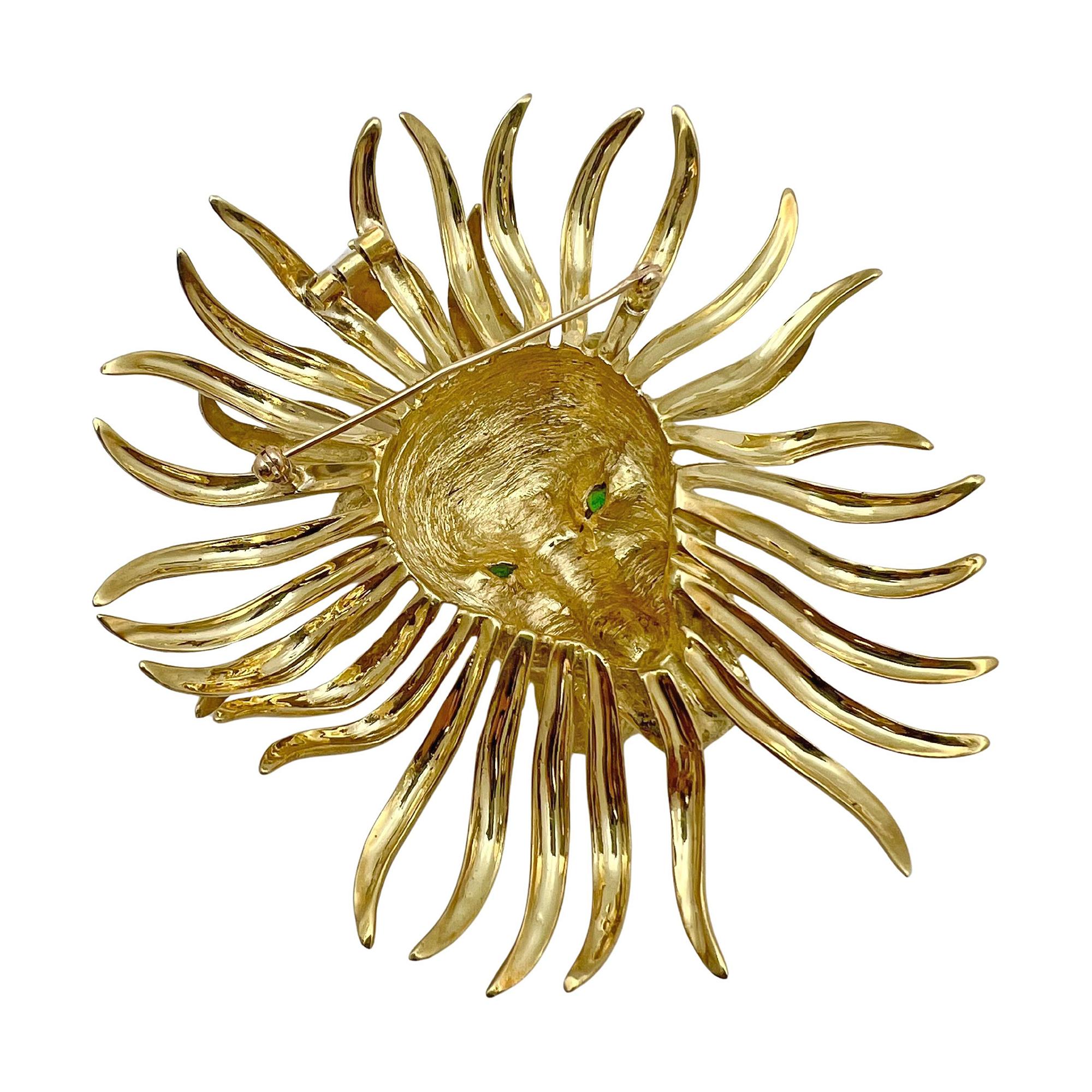 Cartier vintage large lion mask pendant brooch in 18k yellow gold, circa 1970s. Whimsical face is a textured raised design with polished free-flowing lions mane. The eyes are set with round faceted emeralds. Option to be worn as a pendant or brooch