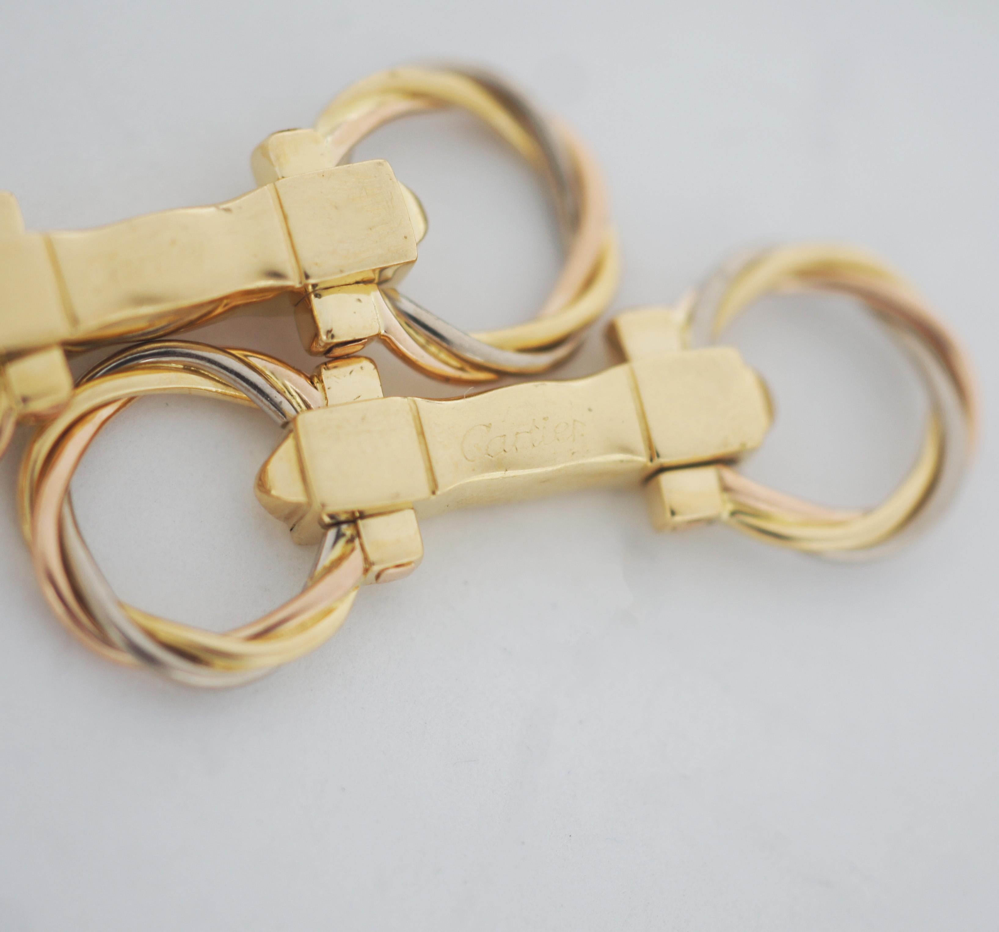 Artikulierte Cartier Trinity Manschettenknöpfe in 3 Goldsorten, bestehend aus 2 gedrehten Ringen in Gelbgold, Roségold und Weißgold.
Signatur: Cartier und nummeriert.
Ca. 1,5