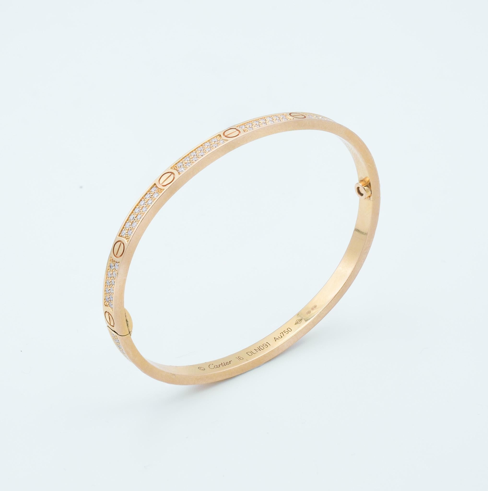 La pulsera presentada es una elegante e icónica pieza de joyería de Cartier, conocida como la Pulsera del Amor. El diseño de la pulsera presenta el clásico motivo de tornillos de la colección Love, que simboliza un vínculo sellado y seguro,