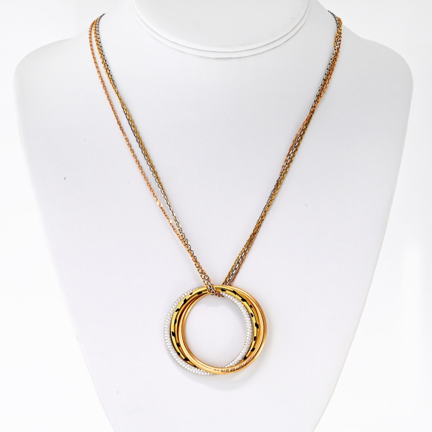 Ce collier de la Trinité de Cartier présente des anneaux tricolores entrelacés, ornés de laque noire et rehaussés d'environ 1,00 carat de diamants ronds de taille brillant. Les diamants sont de couleur F et de pureté VVS-VS, offrant un éclat et une