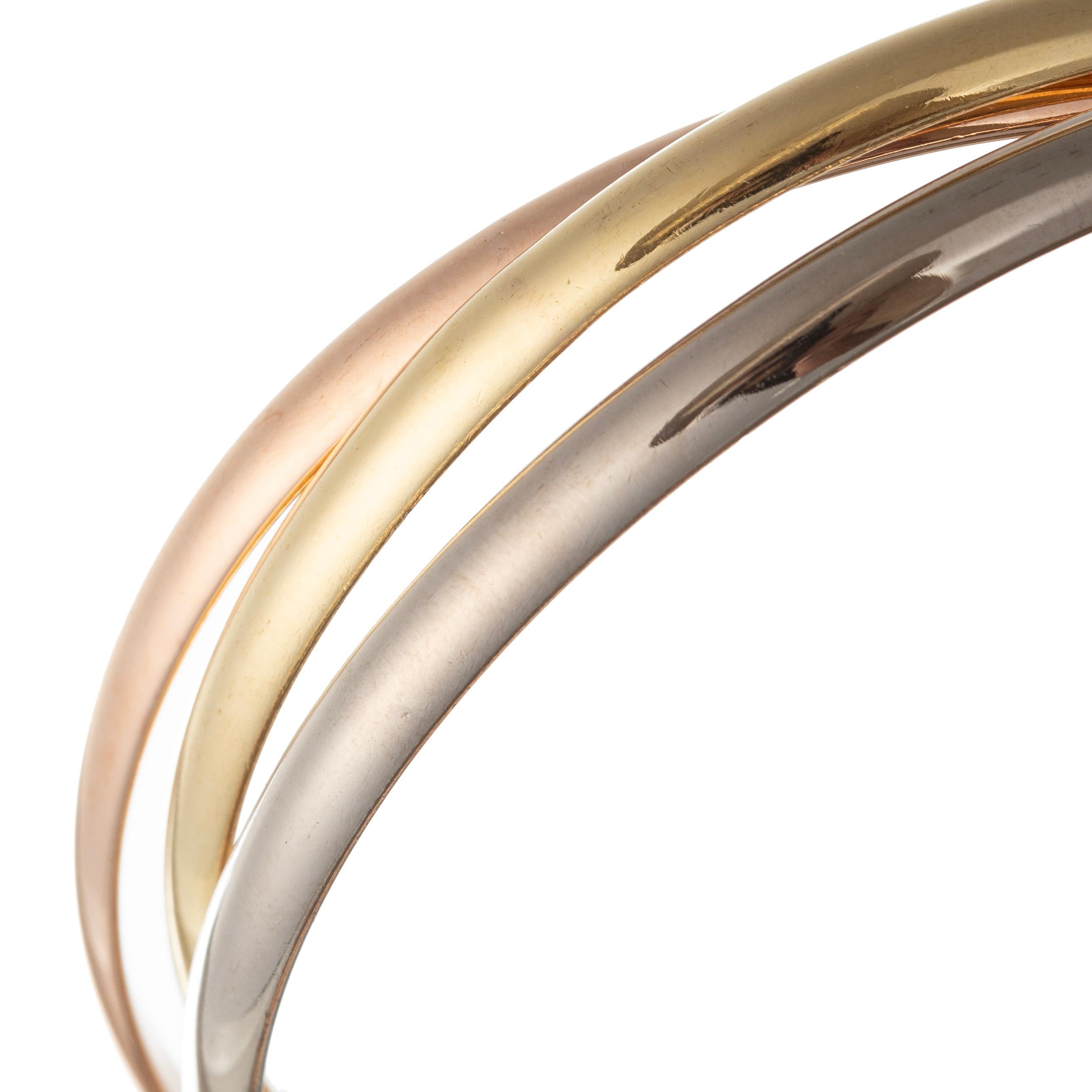 The Trinity rolling bangle bracelet trio in 18 karat yellow gold, pink rose gold, and white gold. Polished finished measuring 4.5mm in width and 2 1/2 inches in diameter.  Signed '@MD CARTIER FQ0510'.  