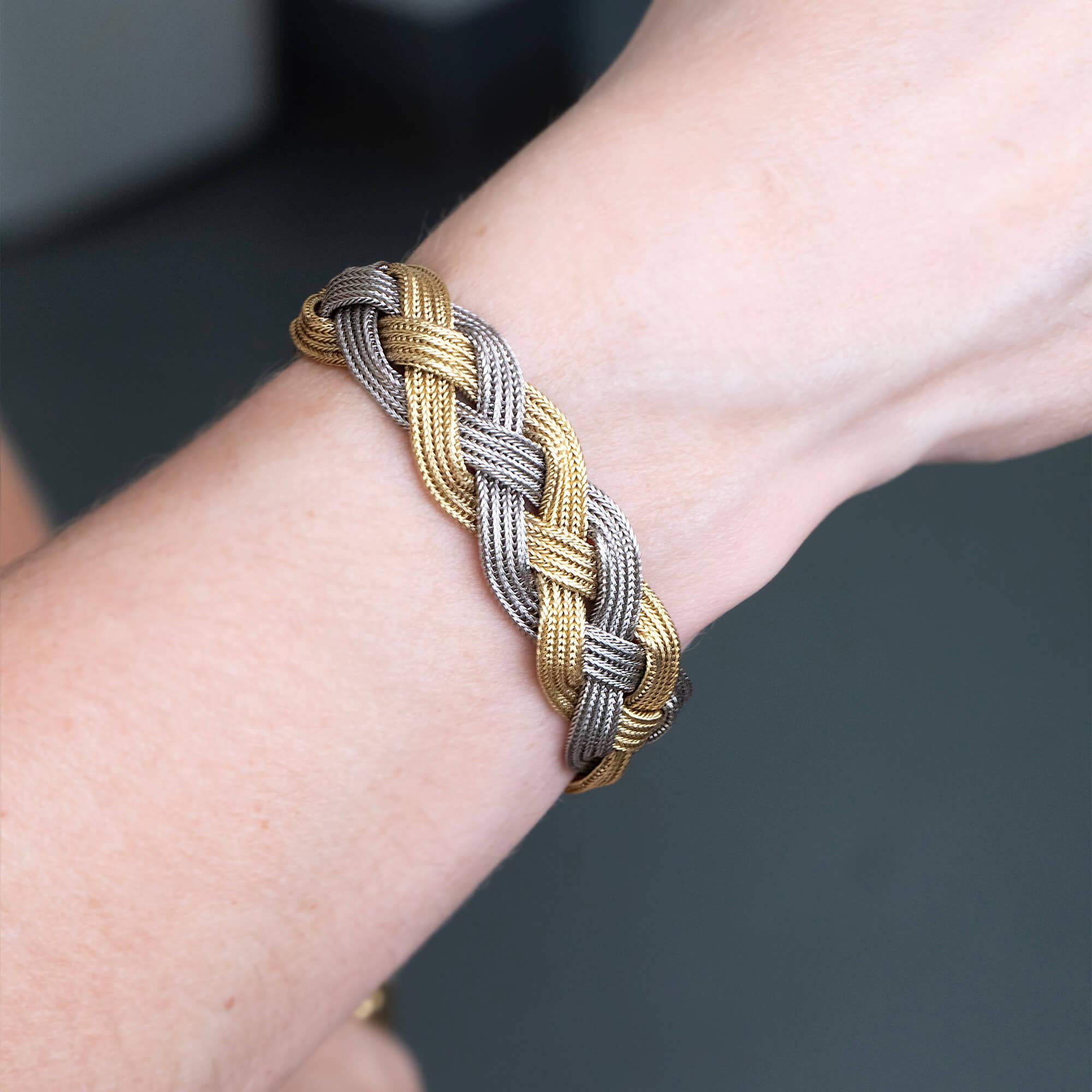 An original Cartier bracelet crafted in 18k two tone gold, featuring three strands of joined foxtail links in a plaited formation, secured by a hidden tongue and box clasp with a figure eight clasp. Hallmarked 750 with English import stamp dated