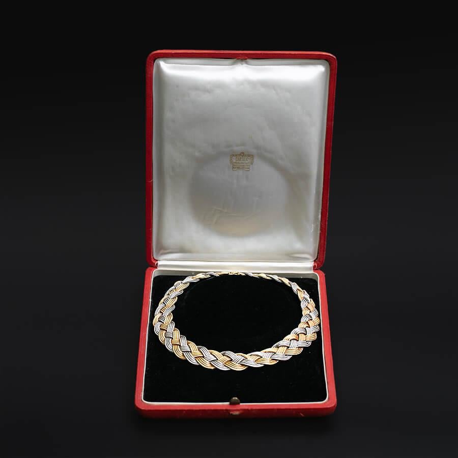 Un originale girocollo Cartier realizzato in oro 18 bicolore, con tre fili di maglie a coda di volpe uniti in una formazione a treccia, assicurati da una chiusura nascosta con linguetta e scatola a forma di otto. Marchio 750, importazione inglese e