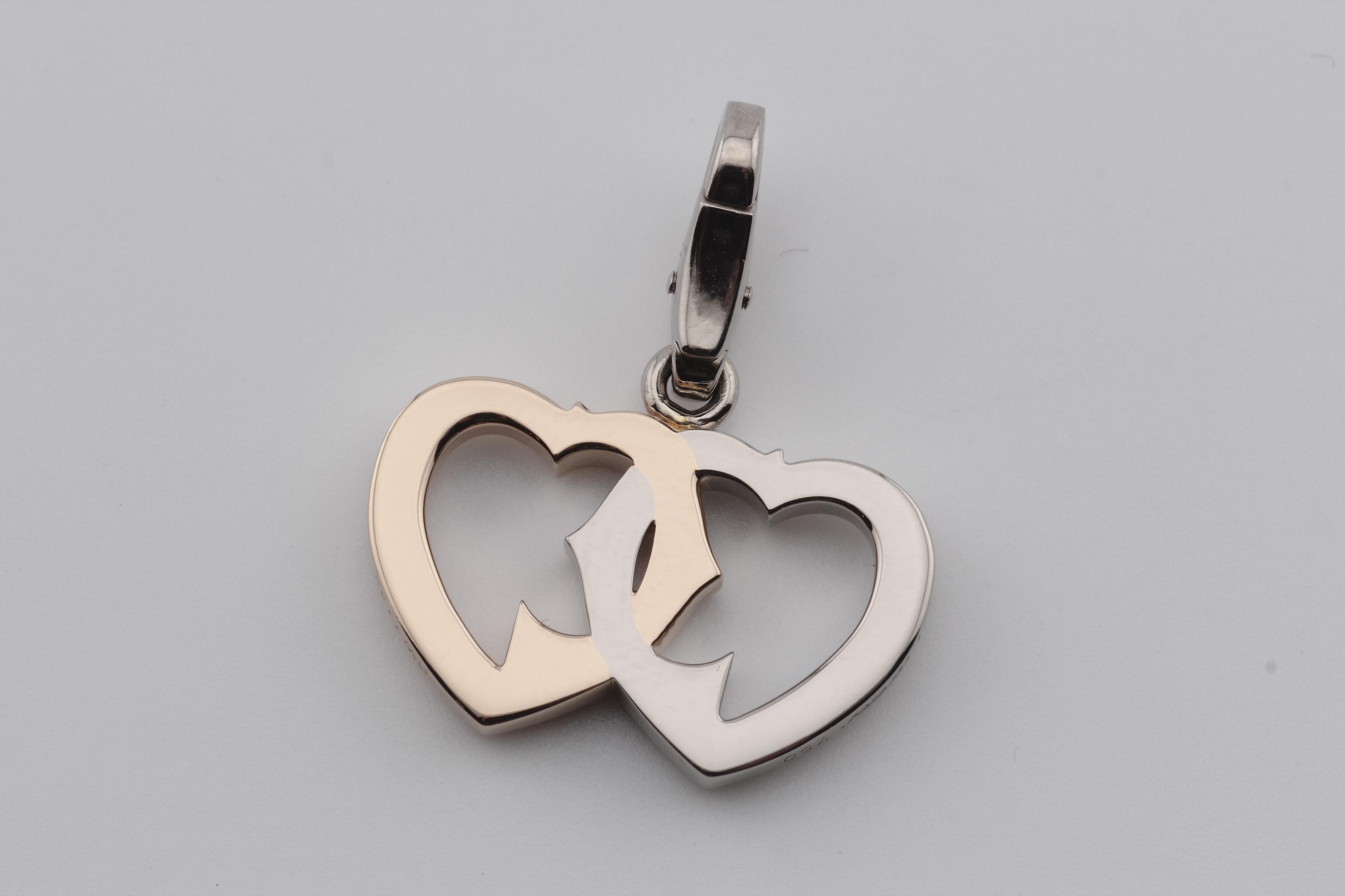 The Cartier 18 Karat White and Rose Gold Intertwined Double Heart Logo Charm is a stunning and symbolic piece of jewelry that beautifully encapsulates the essence of love and elegance. Crafted with meticulous attention to detail by the renowned