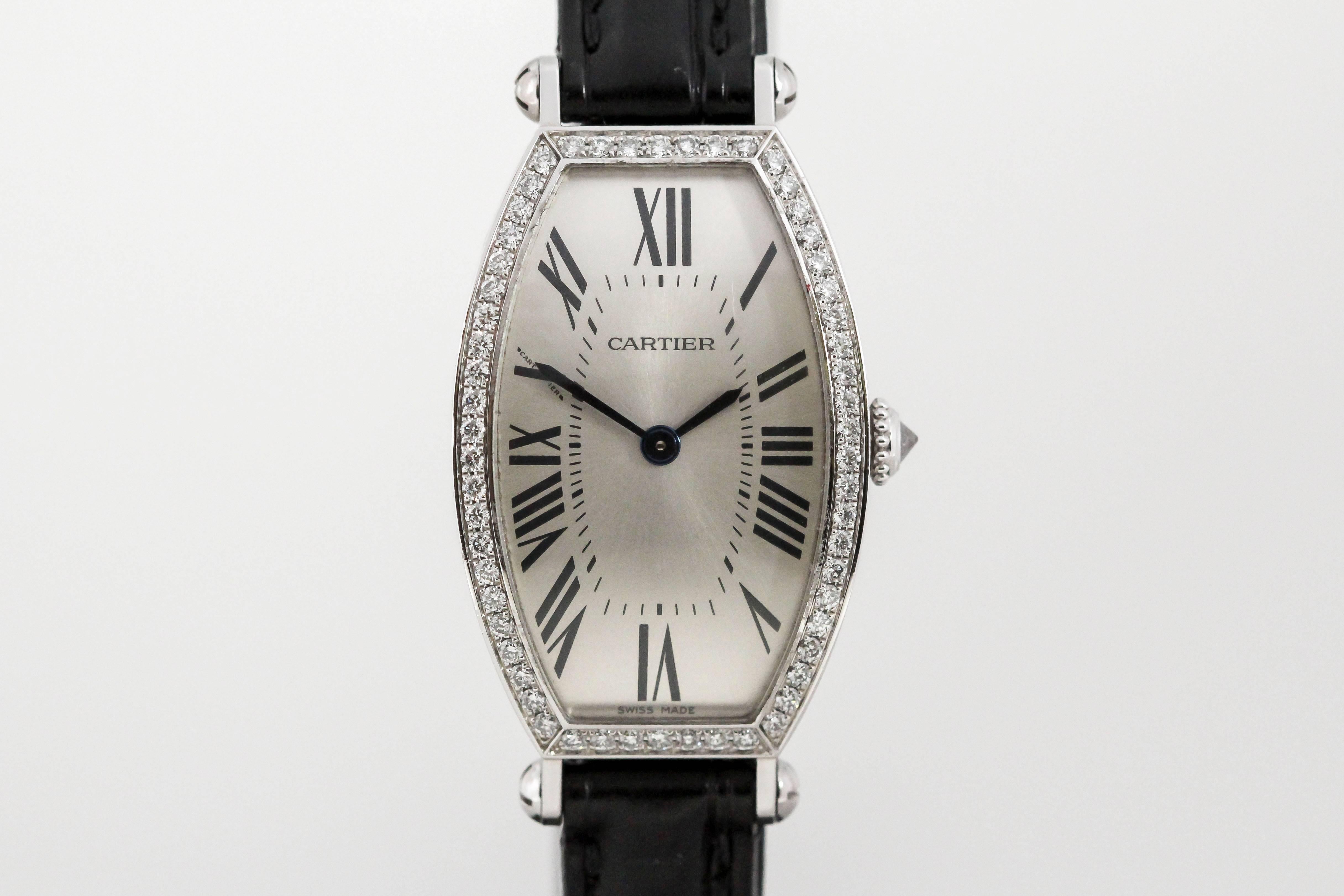 Cartier small Tonneau 18K white gold and diamond case, guilloche dial, manual wind movement and is on a black Cartier strap with 18k white gold deployant Cartier clasp. 