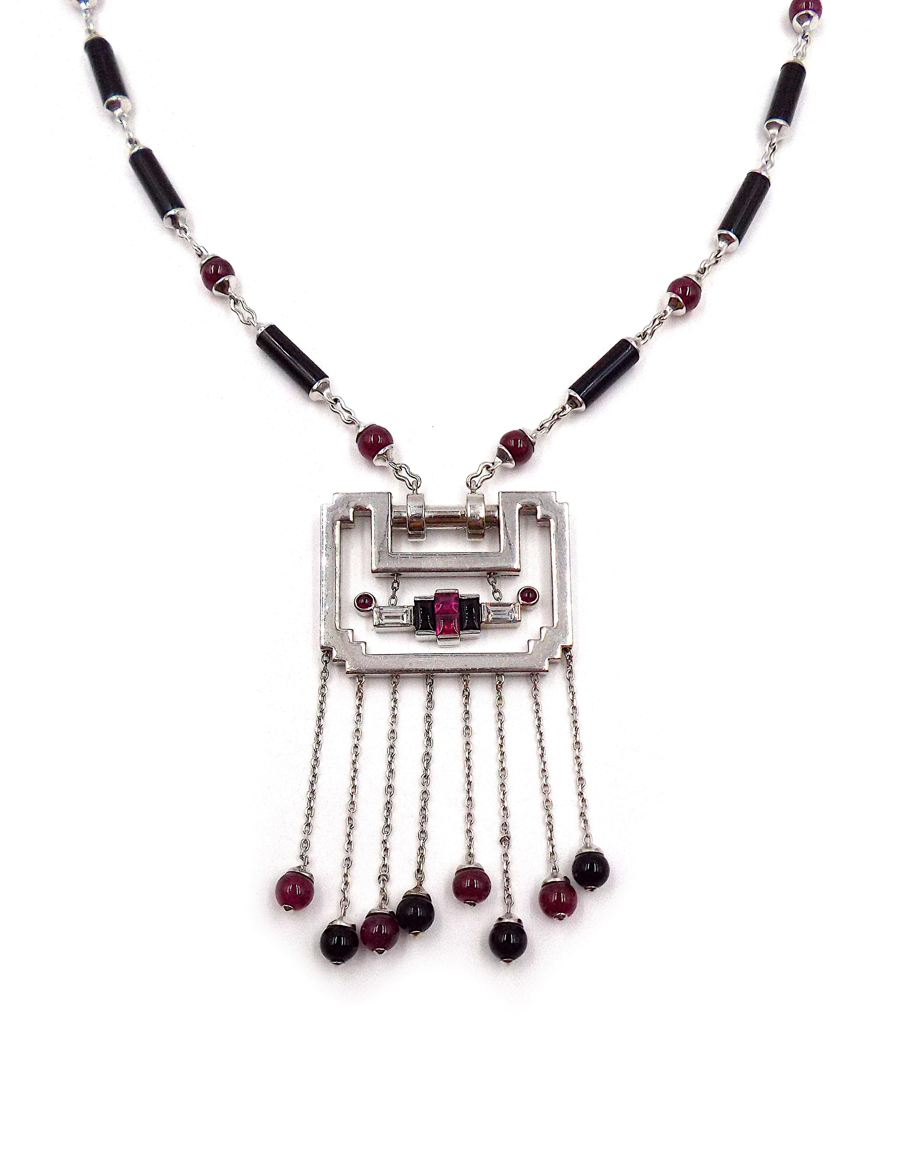 Suspending a pendant, designed as an 18k white gold open frame with fringe enhanced by ruby and onyx bead terminals, to the neckchain designed as an alternating series of onyx barrel-shaped links spaced by ruby beads, 17 1/4 ins., with French assay