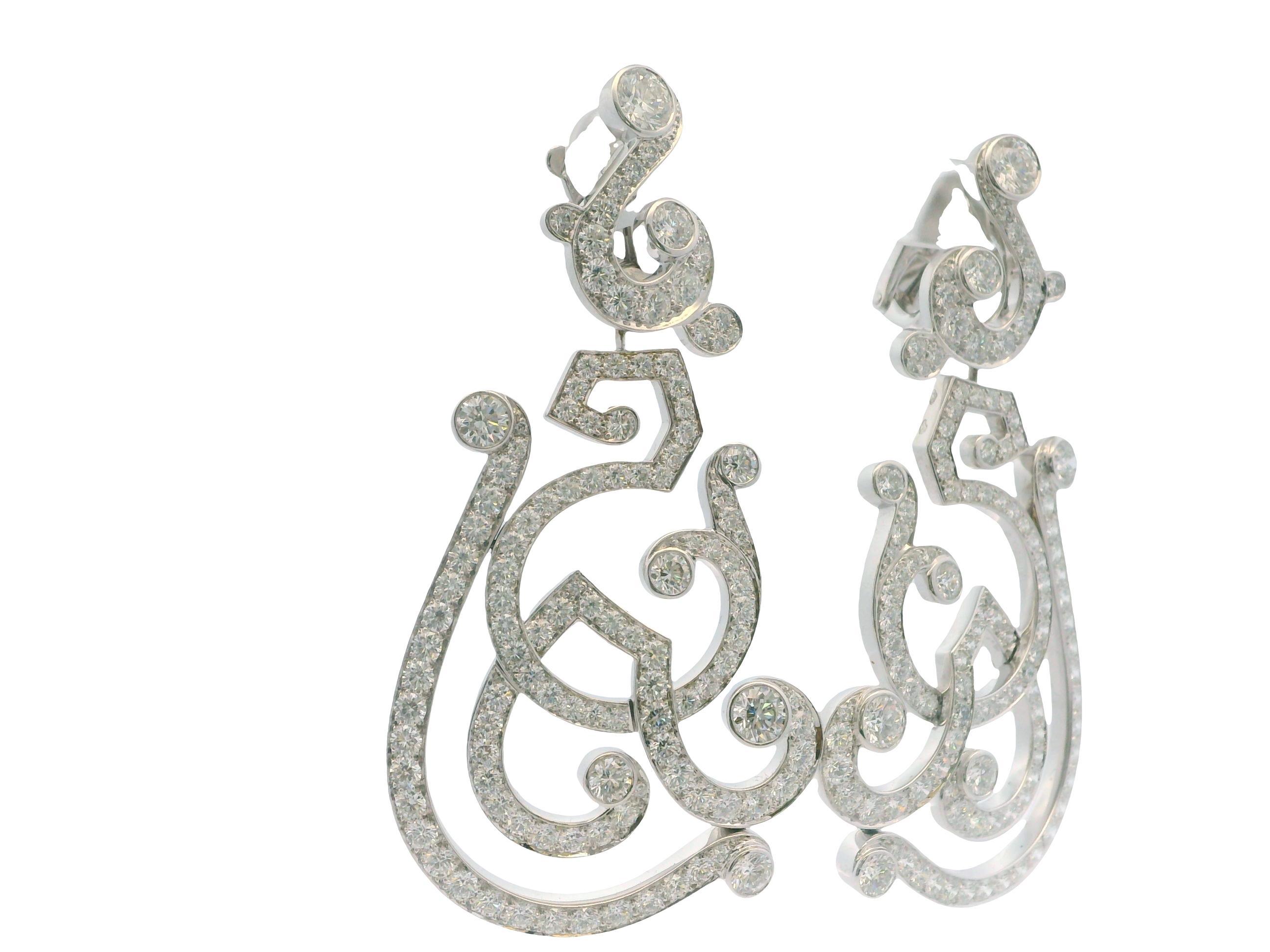 Ces exquises boucles d'oreilles Cartier sont magnifiquement réalisées en or blanc 18 carats et présentent un motif tourbillonnant complexe qui capte le regard. Ornés de diamants blancs ronds étincelants, ils ont un poids total de diamants de 12,0