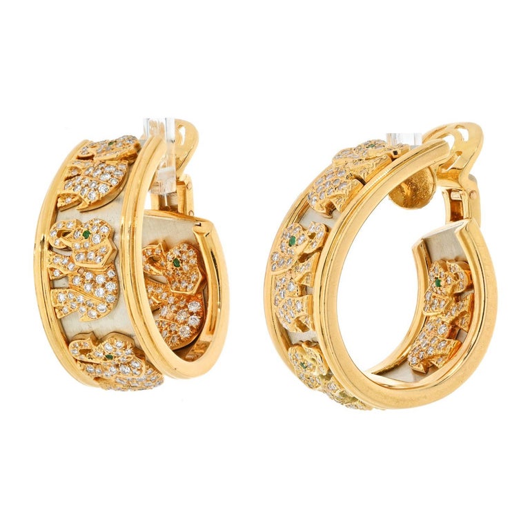 A true collector’s piece, each of these Cartier earrings is designed as a wide hoop featuring diamond elephants, set against a gold background within high polished gold frame. This pair of earrings is an iconic piece of jewelry that exuberates