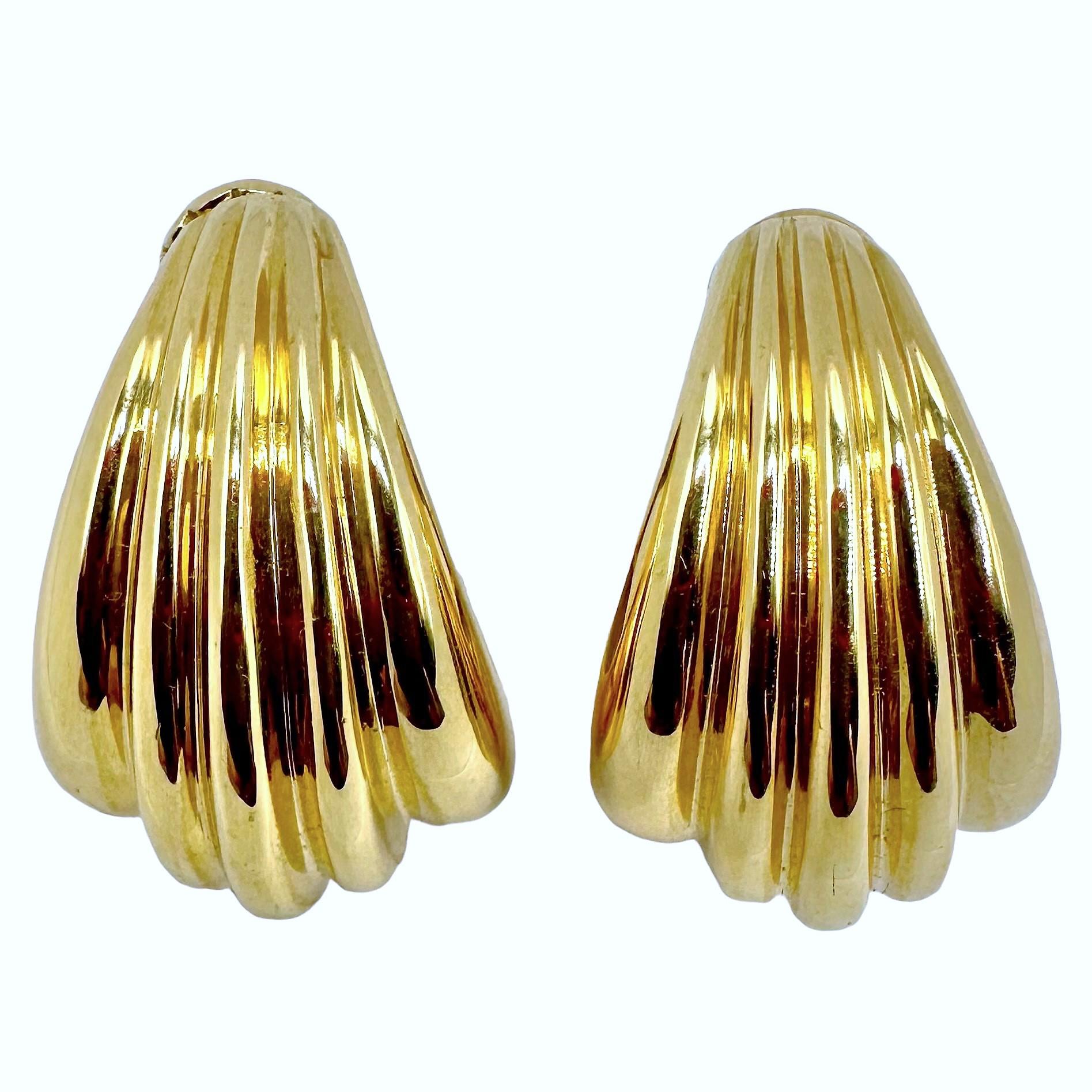 This tasteful pair of Cartier fluted hoop earrings would be a welcome addition to any lady's fine jewelry collection. Measuring  1 1/8 inches long by 
3/4 inch across at the widest point. The earring clips are stamped 750 indicating 18K. On the rear