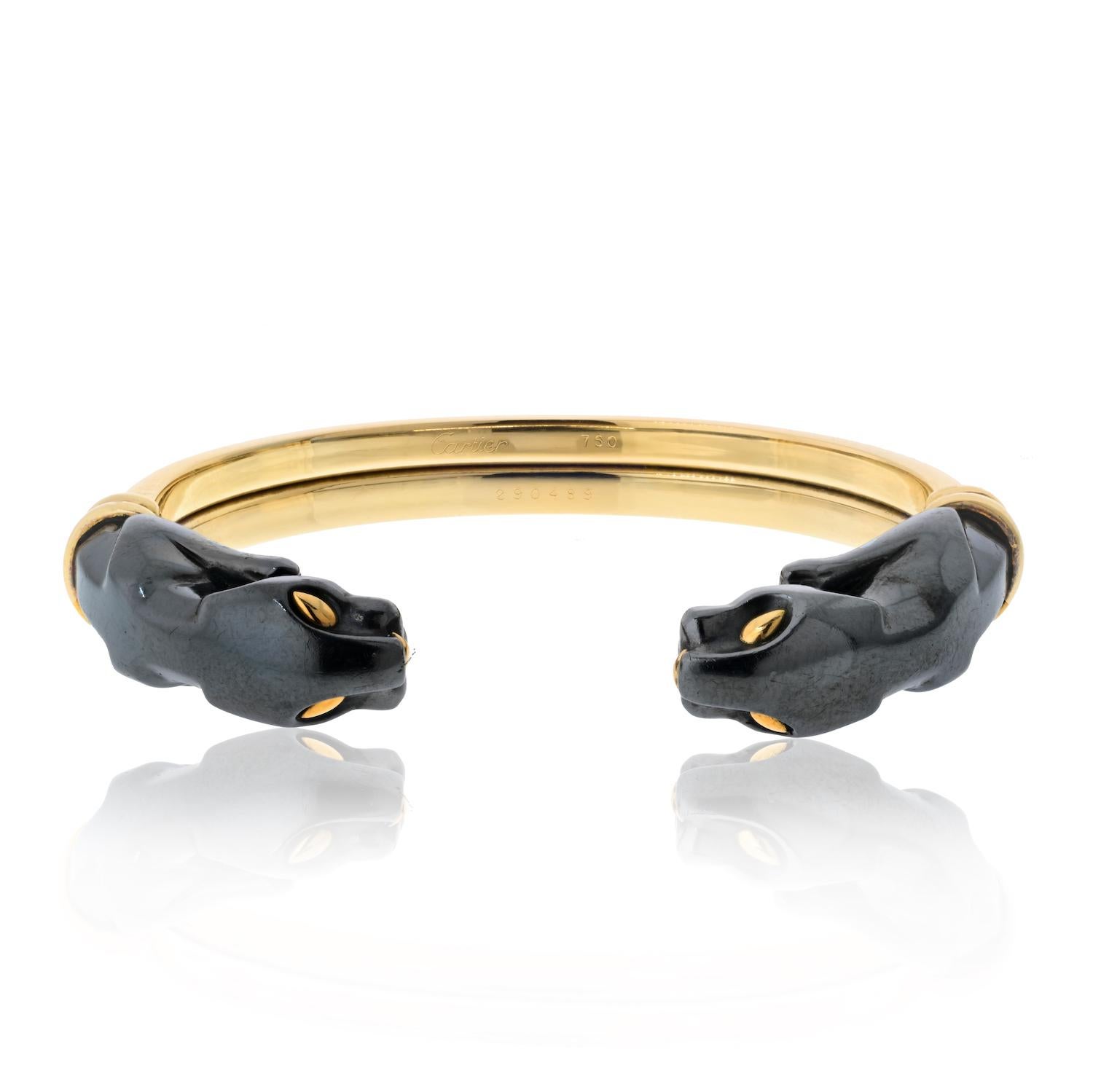 An 18k yellow gold and silverium cuff bracelet from the Panthere de Cartier collection. The bracelet is composed of 2 silverium Panther heads facing each other, joined together by the polished yellow gold cuff. The bracelet would fit a wrist size of