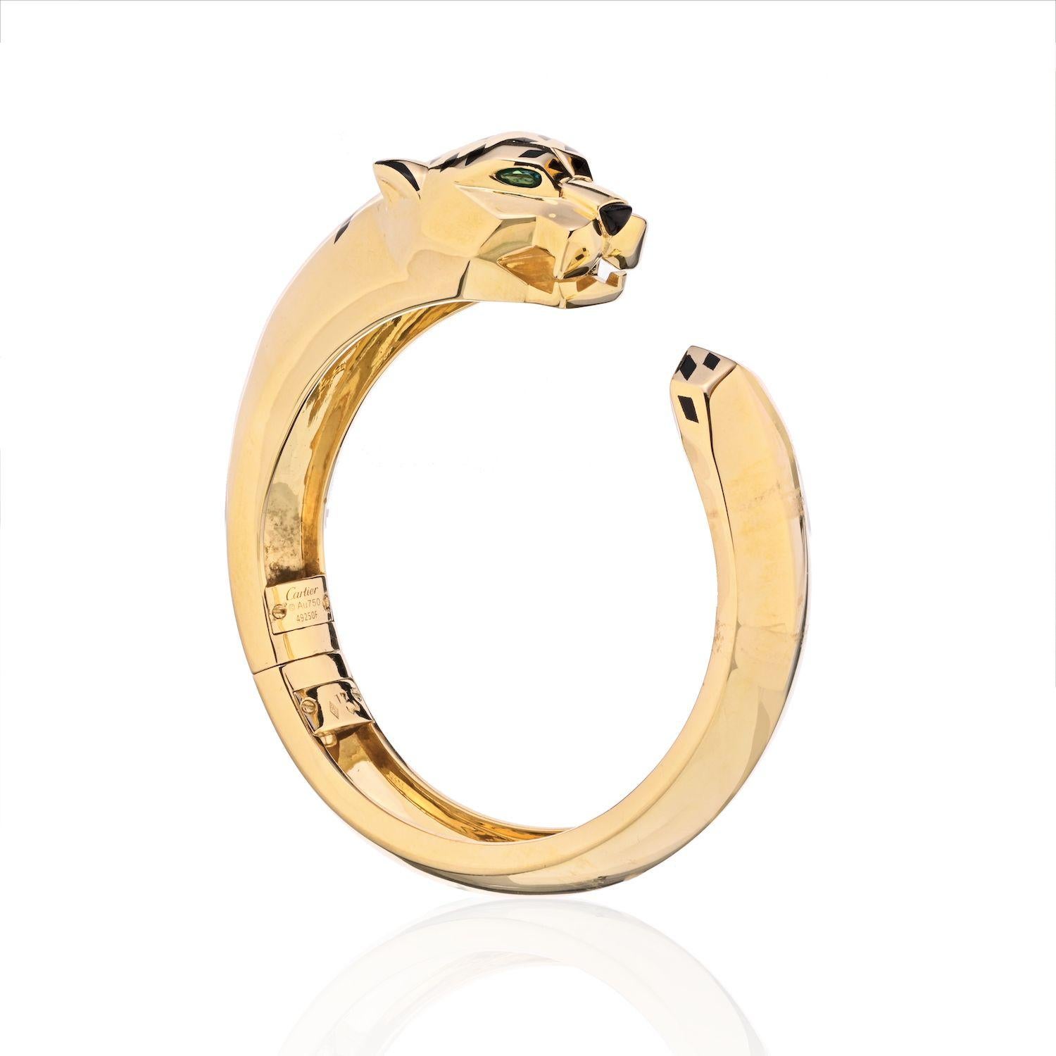 Cartier 18K Gelbgold Panthere Größe 17 Armspange Armband.
Ein Cartier Panthere-Armreif mit Scharnier aus 18 Karat Gold, der in einem skulpturalen Pantherkopf mit Peridot-Augen und Onyx-Nase gipfelt, der mit schwarzen Lackflecken verziert ist.
Die
