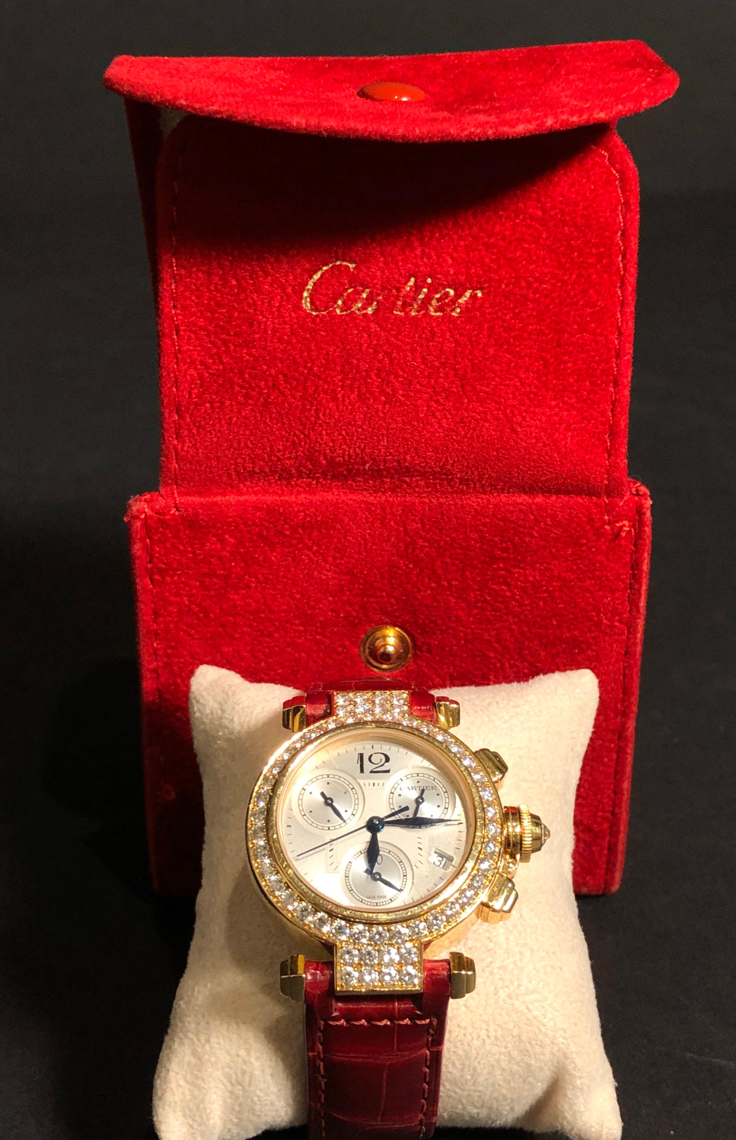 Cartier Pasha 18 karat yellow gold and diamond ladies watch on red leather strap band - Quartz movement. Three sub dials and date window. 18-karat yellow gold with factory diamond bezel and diamonds that flow over the lugs. Red strap band with
