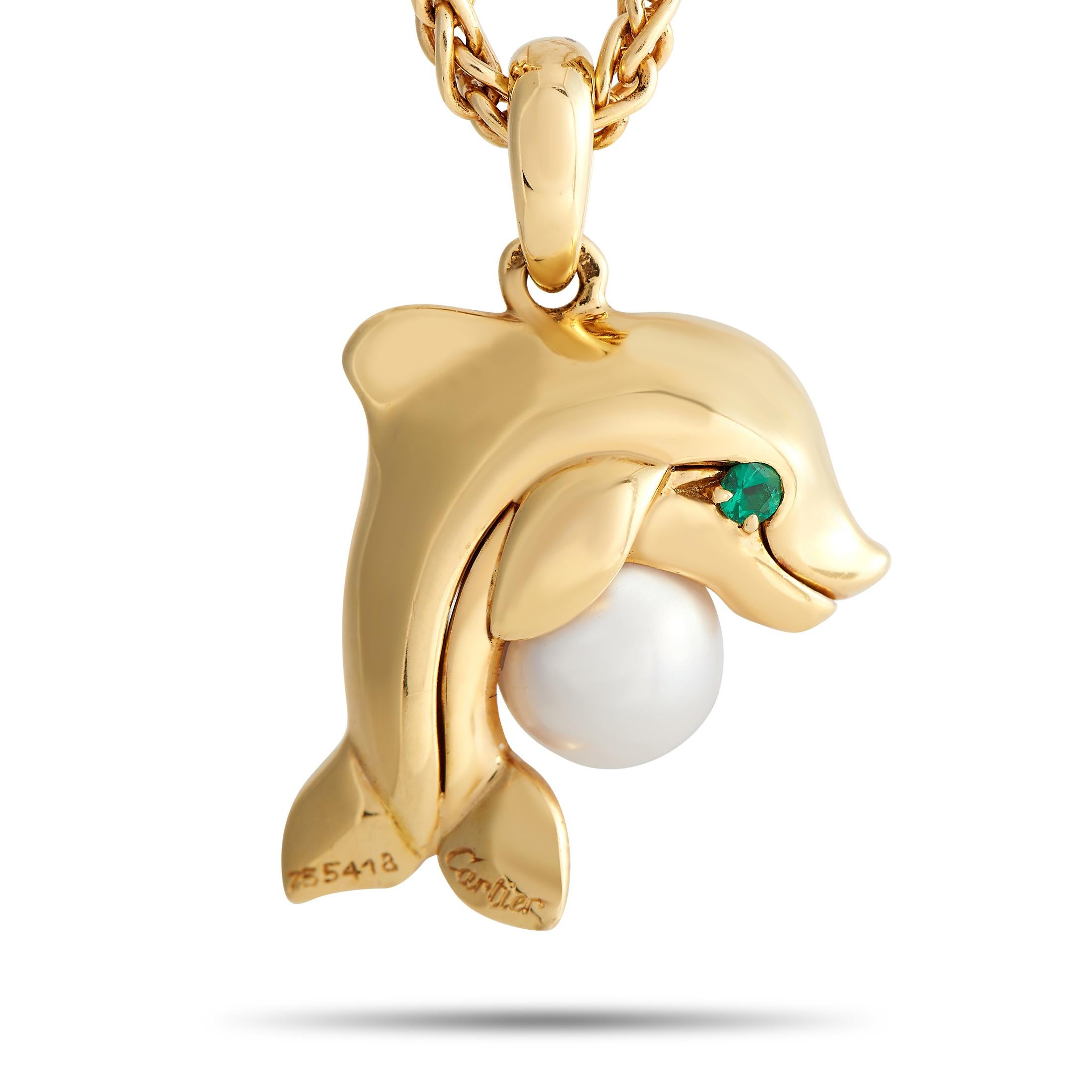 This 18K Yellow Gold Cartier necklace is incredibly captivating. Suspended from a sleek 16” chain, you’ll find a dolphin-shaped pendant accented by green gemstone eyes and a stunning pearl accent. It measures 1” long and 0.75” wide - the perfect