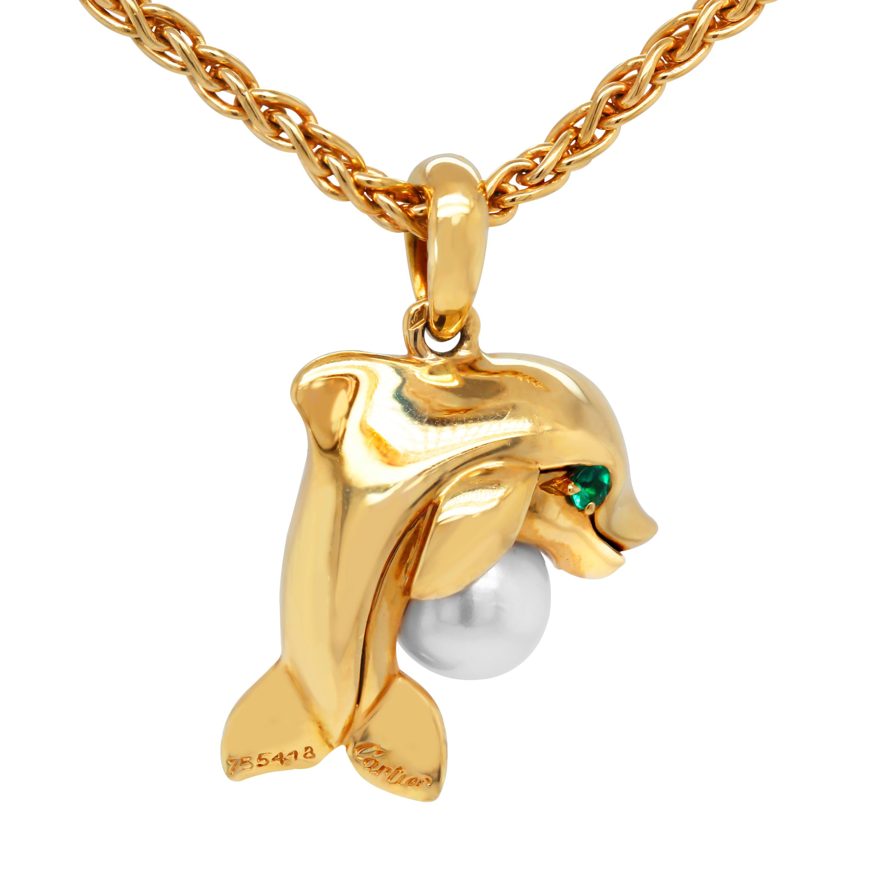 Cartier 18K Yellow Gold Pearl Emerald Dolphin Pendant Necklace

Eyes of the dolphin are Emeralds with a round pearl being held.

Pendant is 1.04 inch in length by 0.57 inch width.
Chain is 16 inches in length.

Signed Cartier