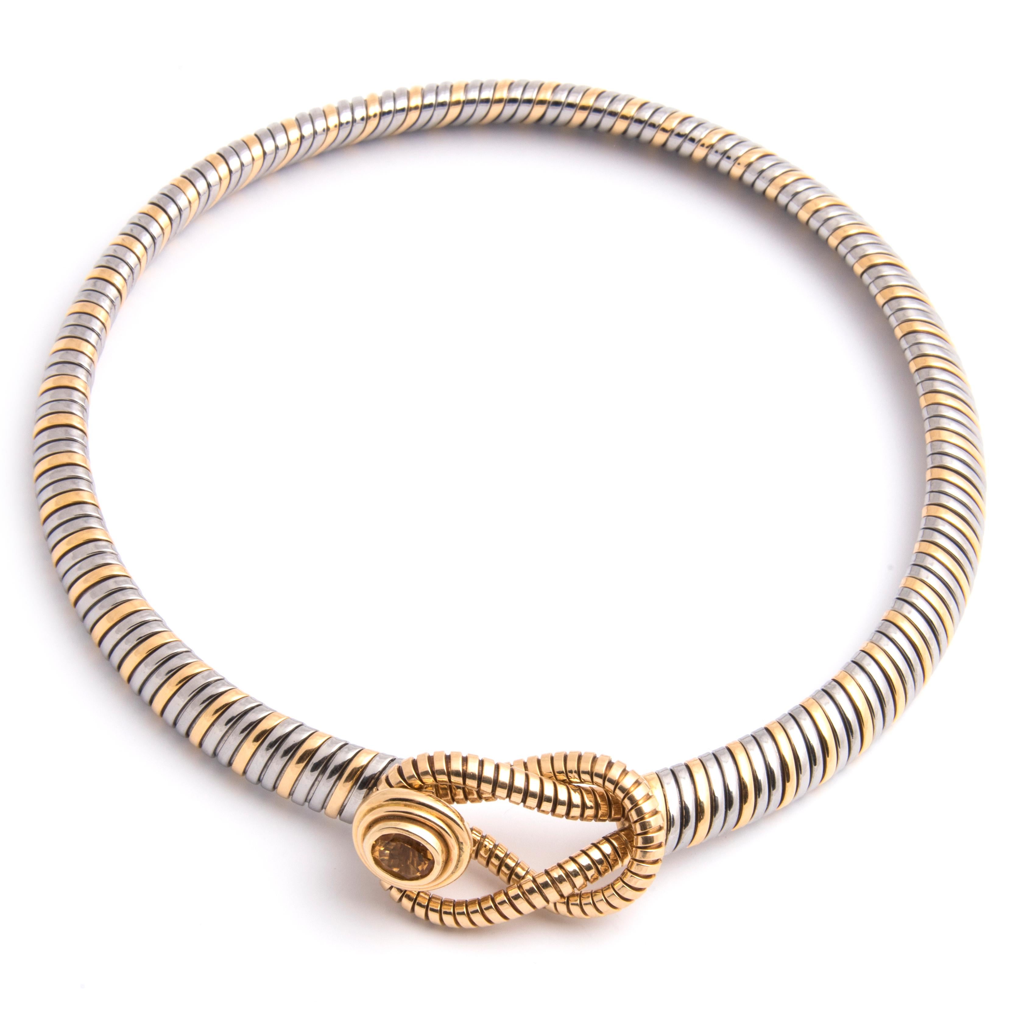 A Tubogaz chocker necklace by Cartier in 18k yellow gold and steel. The loops at each end forming a clasp with the button set with an oval citrine
Signed Cartier, stamped Or et Acier (Gold and steel), maker's mark, French import marks and numbered