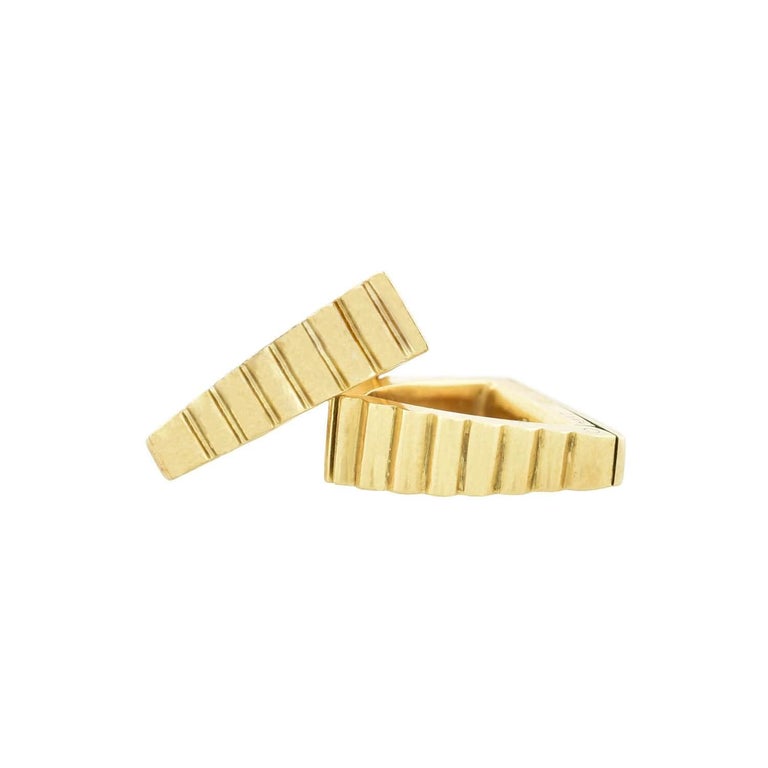 A striking pair of cufflinks from famed maker Cartier! Crafted in vibrant 18kt yellow gold, these cufflinks have a unique hinged triangular design. The visible surface of the cufflinks displays a fluted and slightly graduated look, clamping securely