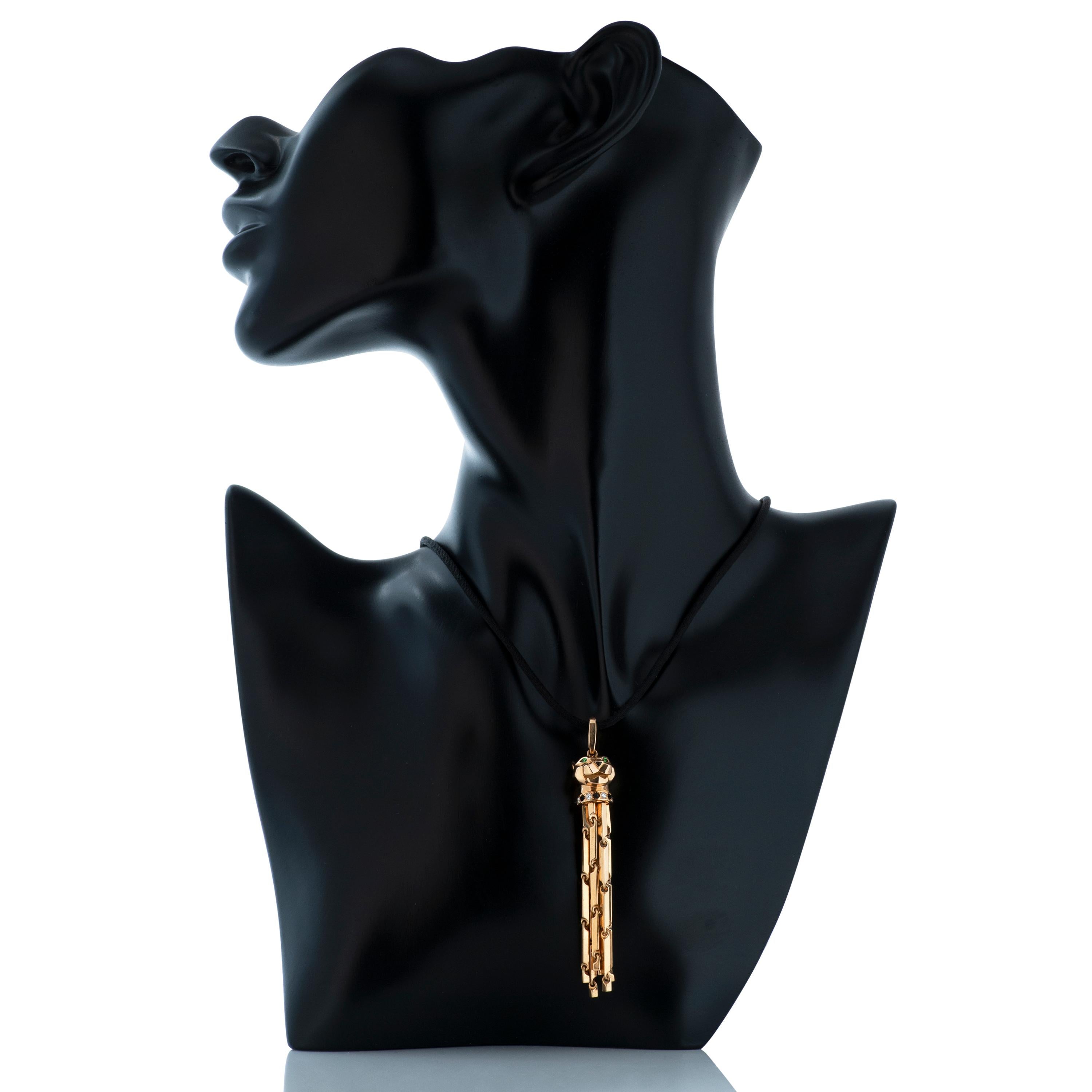 Cartier 18k yellow gold diamond, tsavorite and onyx Panthere pendant on adjustable black cord necklace with 18k yellow gold clasp.  

This Cartier pendant features a panther head with gold hanging tassels.  The panther head contains 7 round diamonds