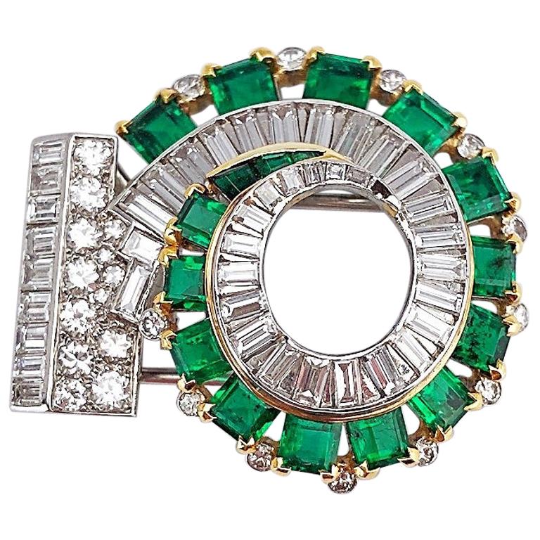 Circa 1930's. Platinum and 18 karat yellow gold swirl brooch set with approximately 3.50 carats of round and baguette cut diamonds, and approximately 6.53 carats of  square emerald cut emeralds.
Double clip brooch  1.5