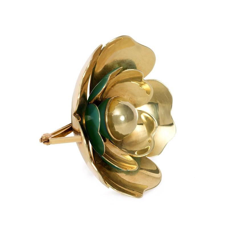 A Retro gold and reflective blue enamel brooch in the form of a flower, in 14k.  Cartier, New York.  See Patent #2199222

(Reflection of the blue enamel off the yellow of the gold makes it appear greenish from certain angles.)