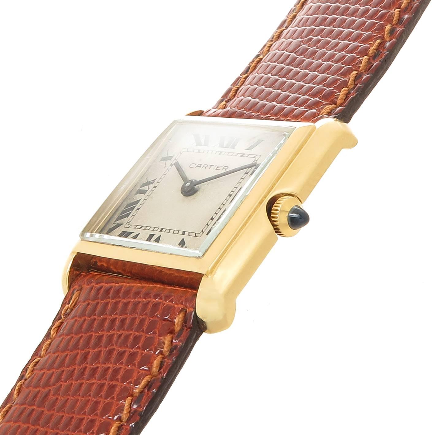 Circa 1950s Cartier Classic Tank Wrist Watch, 27 X 23 M.M. 18K Yellow Gold case. Bueche Girod 17 Jewel Manual wind, mechanical movement, White Dial with Black Roman Numerals. Sapphire Crown. New JC Perrin France, Brown Lizard Strap, watch length 8