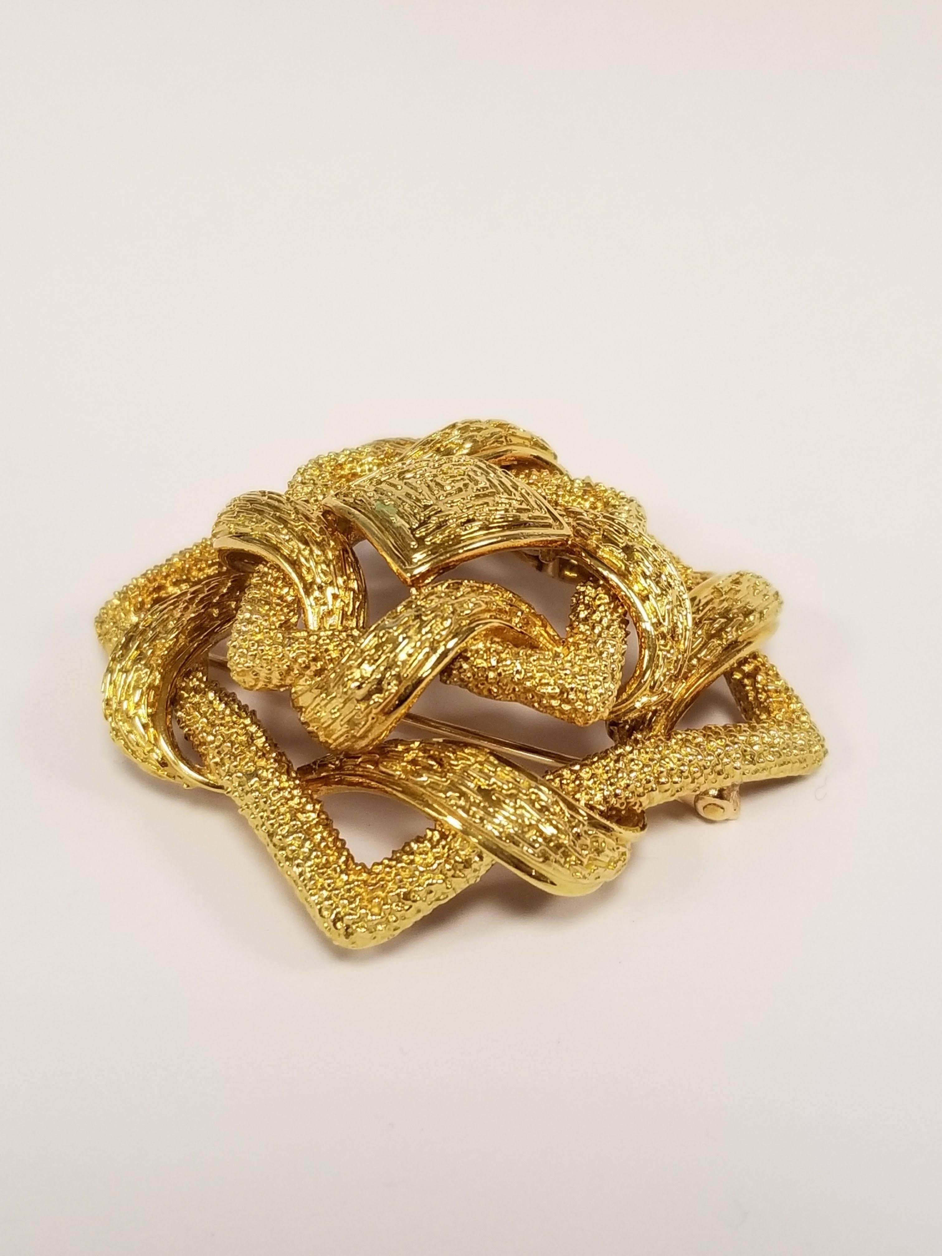 This bold Cartier brooch features a woven knot design, and radiates the peaceful energy of an ancient mandala. Rendered in richly textured gold, this Mid-Century Modern twist on a meditative motif features a marvelously tactile surface and