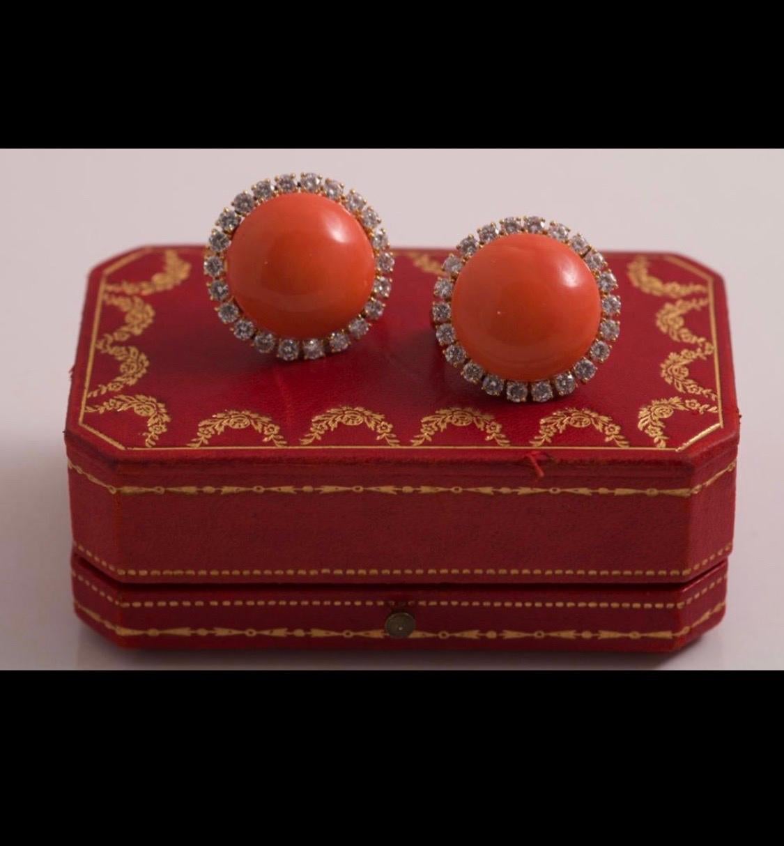 Magnificent Pair of Cartier Corallium rubrum Precious Coral and Diamond Circular Clip Earrings in Yellow Gold, 1960s, fitted in a Cartier case from the period. Each earring of a circular shape features a coral cabochon of a vibrant pinkish-Orange