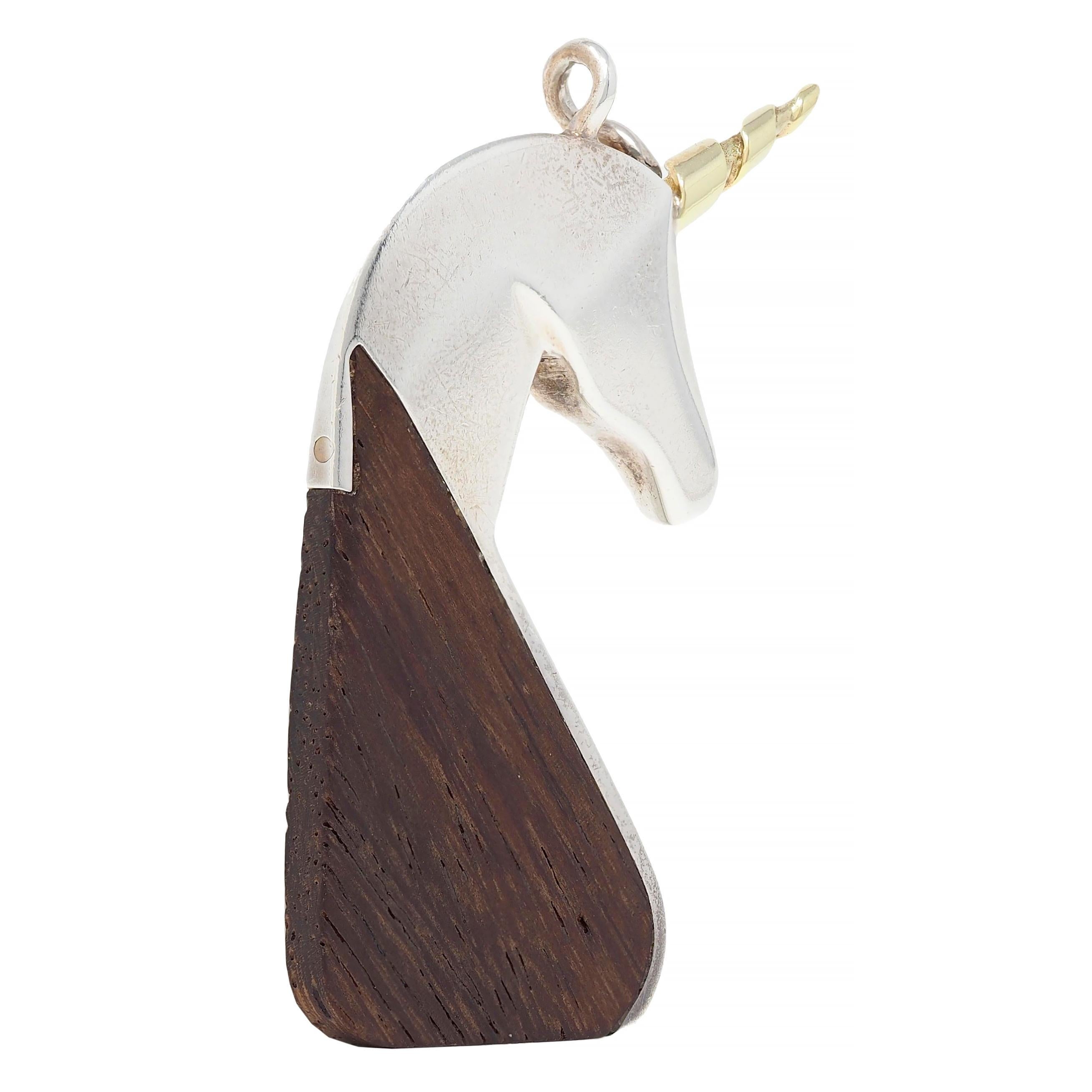 Anhänger mit stilisiertem Einhornmotiv aus Sterlingsilber
Minimalistisch mit dezent facettiertem Kopf und geschnitzter Holzmähne
Dunkelbraun mit durchgehend linearer Maserung
Ergänzt durch ein gedrehtes goldenes Horn
Aufhängung am gedrehten