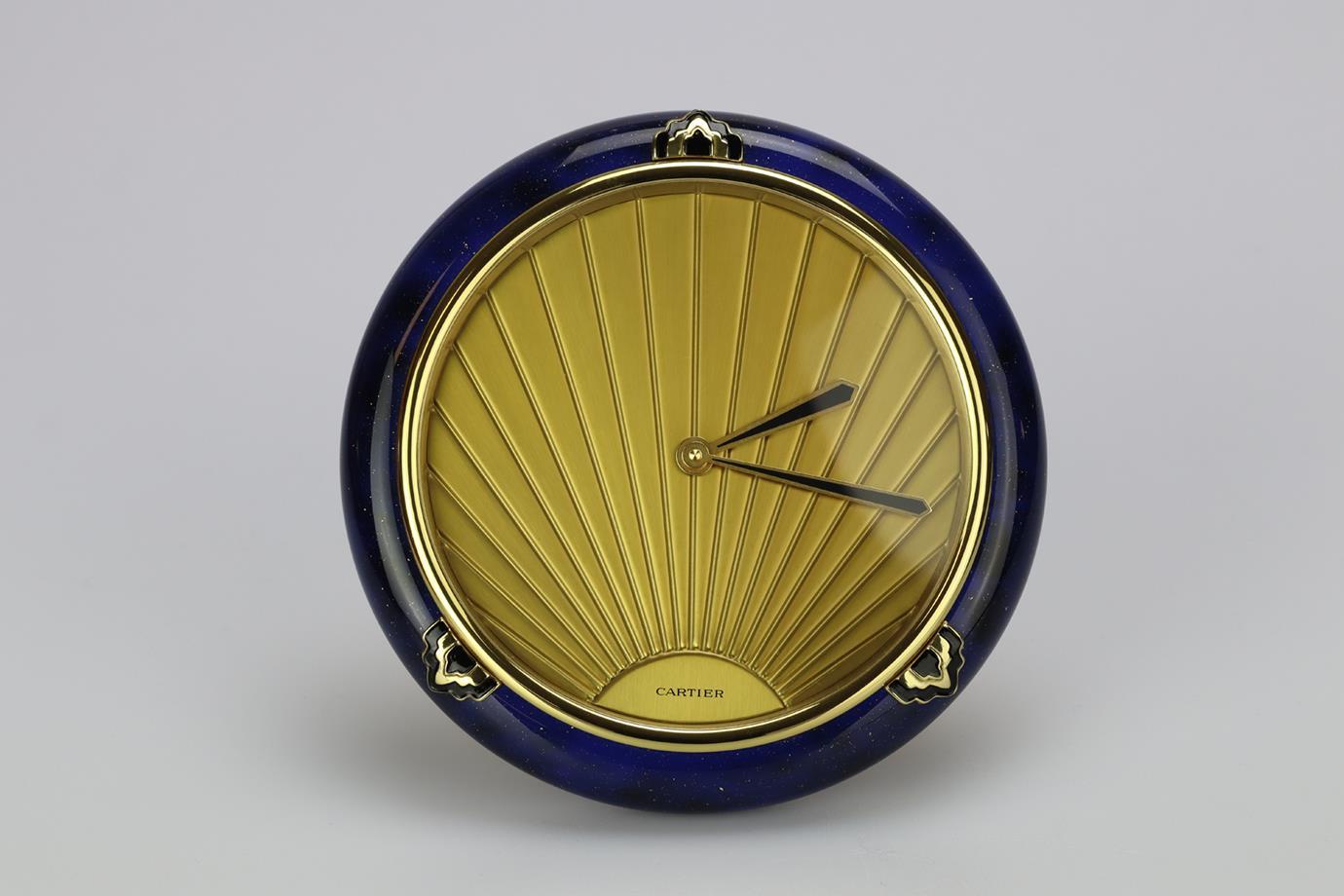 Cartier 1980 Must De Cartier Lapis Art Deco Desk Clock. Blue and gold. Comes with - case, box and valuation from Cartier for insurance. Quartz Movement. Brass case. Golden finish dial. Blue enamel. Diameter: 13 cm. New with tags.