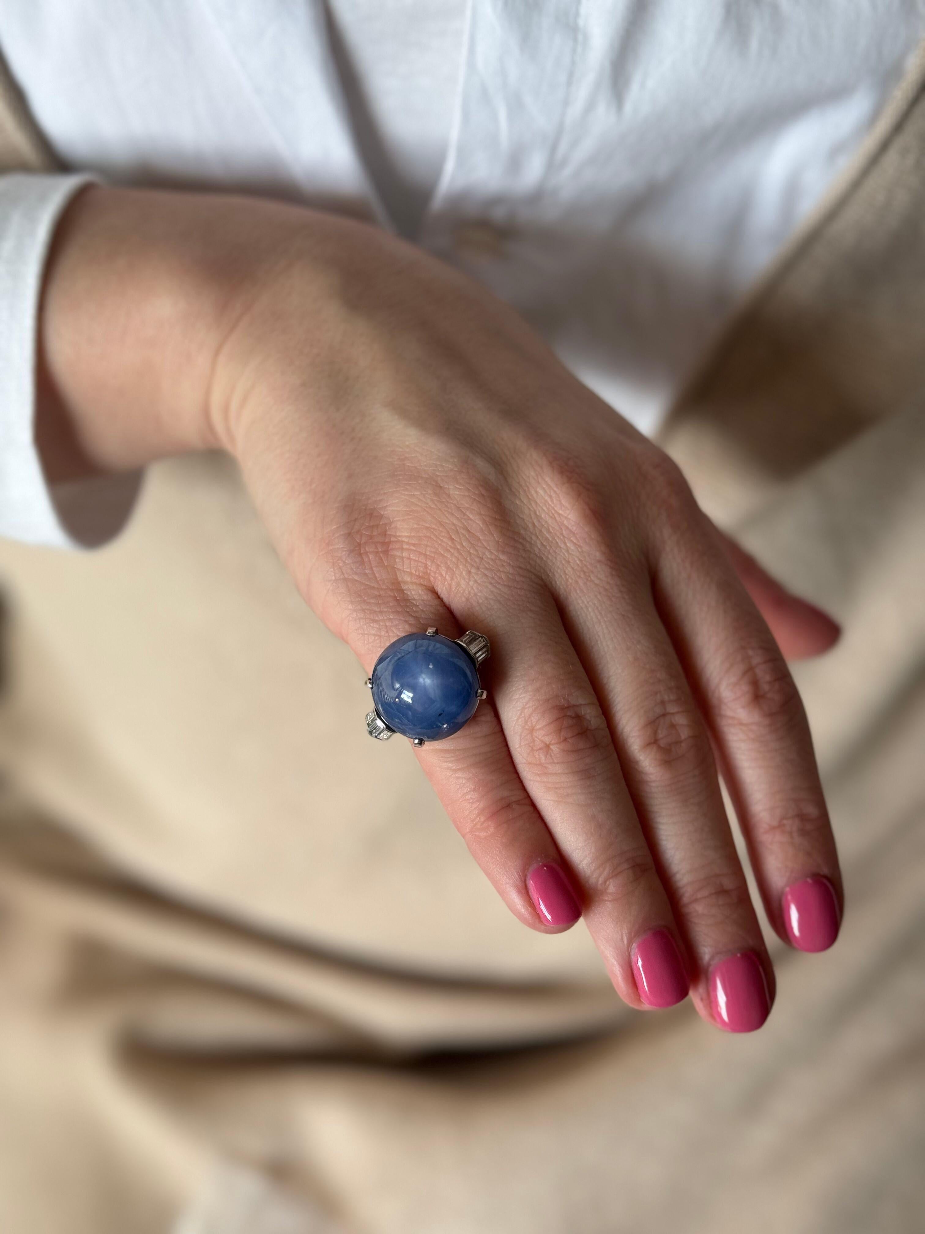 Impressive Cartier platinum ring, featuring center star sapphire cabochon - stone is approx. 53ct by formula, measuring approx. 18.3 x 17.8 x 15mm. Set with side baguette diamonds, approx. 0.48ctw G/VS. Ring size 5.25. Marked Cartier. Weight - 16.9