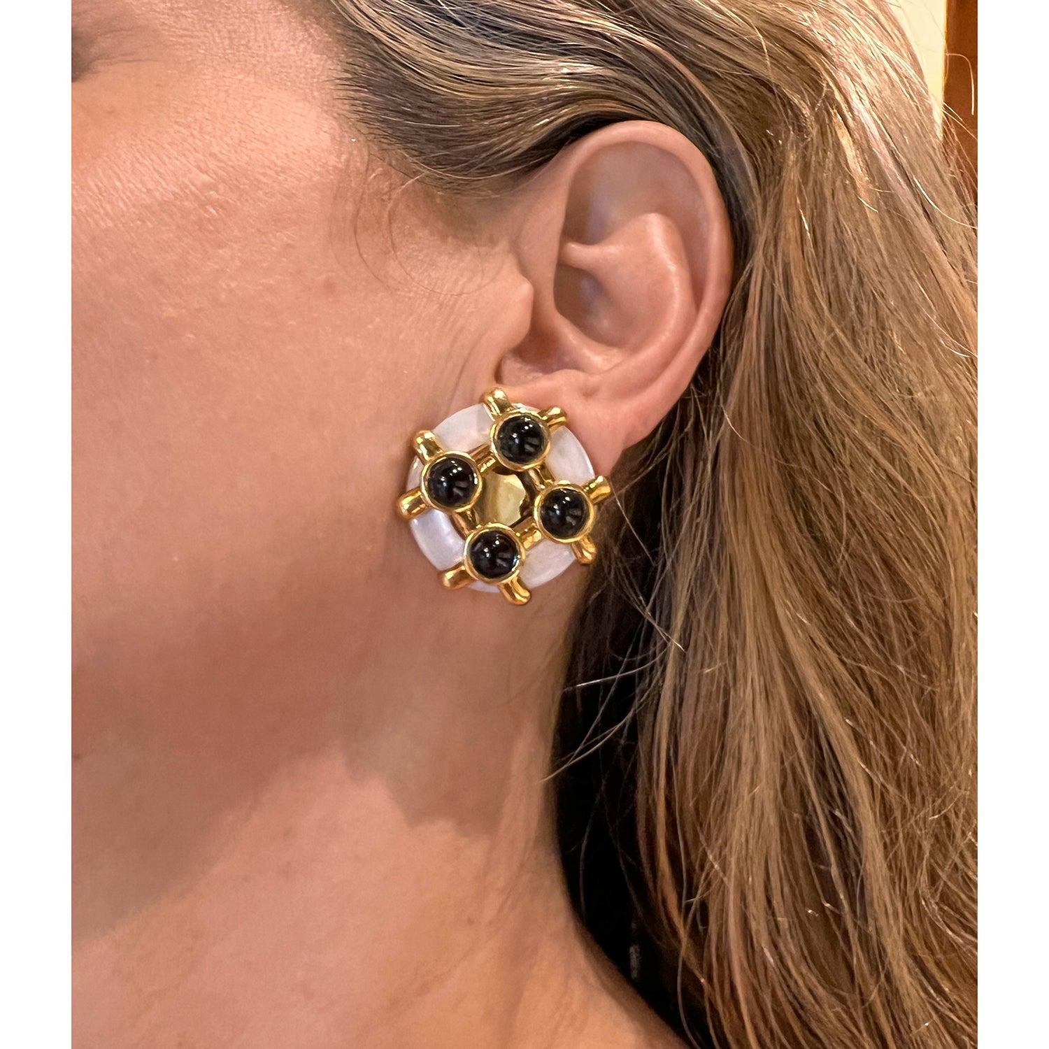 Designed by Aldo Cipullo for Cartier in 1972, these 18k yellow gold earrings feature a raised gold lattice pattern over carved mother-of-pearl accented by four round cabochon-cut black onyx. Clip backs (posts may be added upon customer request).