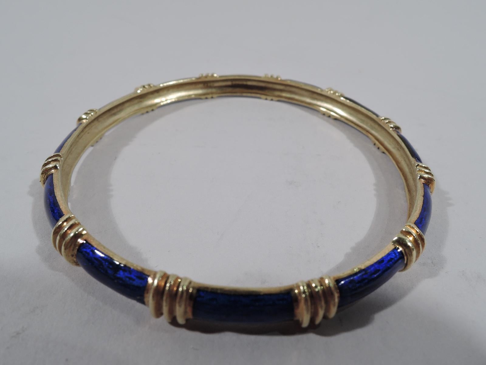 Classic 18k yellow gold and enamel bangle. Exterior royal blue interspersed with raised gold ribbing. United States, ca 1980s. Marked “Cartier 18k”.  
