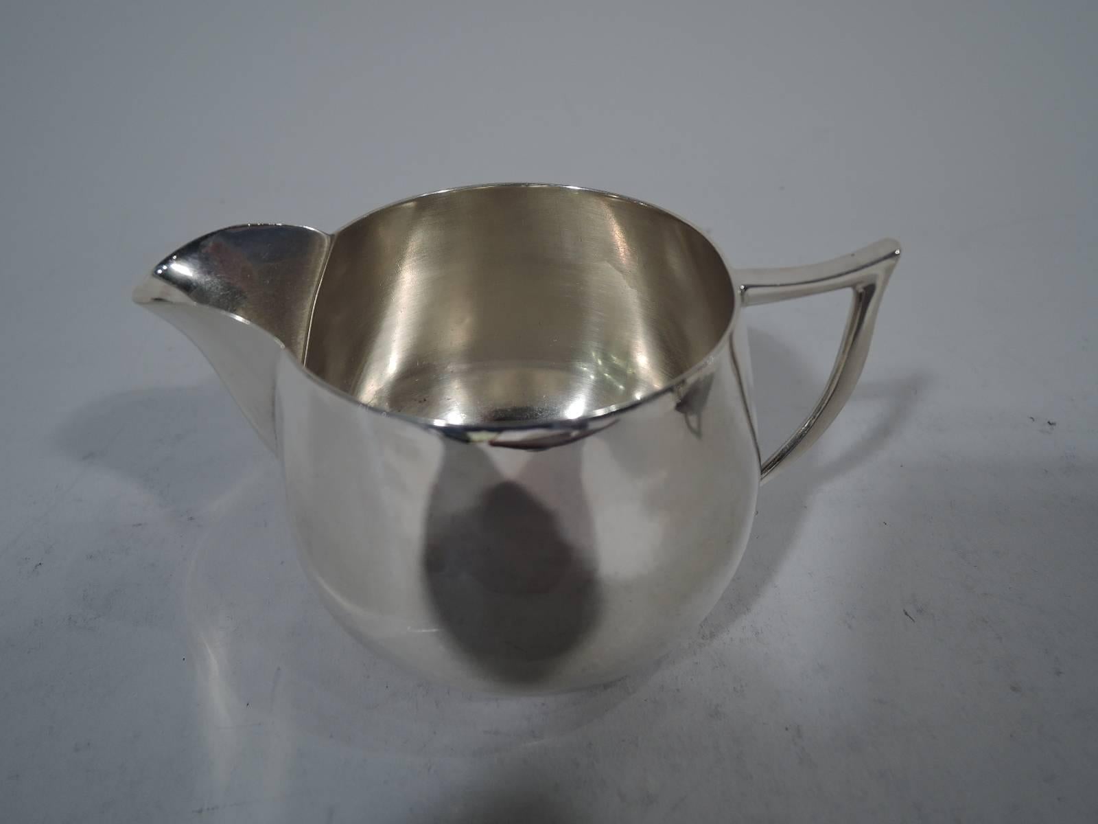 Art Deco sterling silver creamer and sugar. Retailed by Cartier in New York. Upward tapering sides and scrolled bracket handles. Creamer has v-spout. A chic pair. Hallmark includes no. 83, retailer’s name, and maker’s mark Clarence A. Vanderbilt,